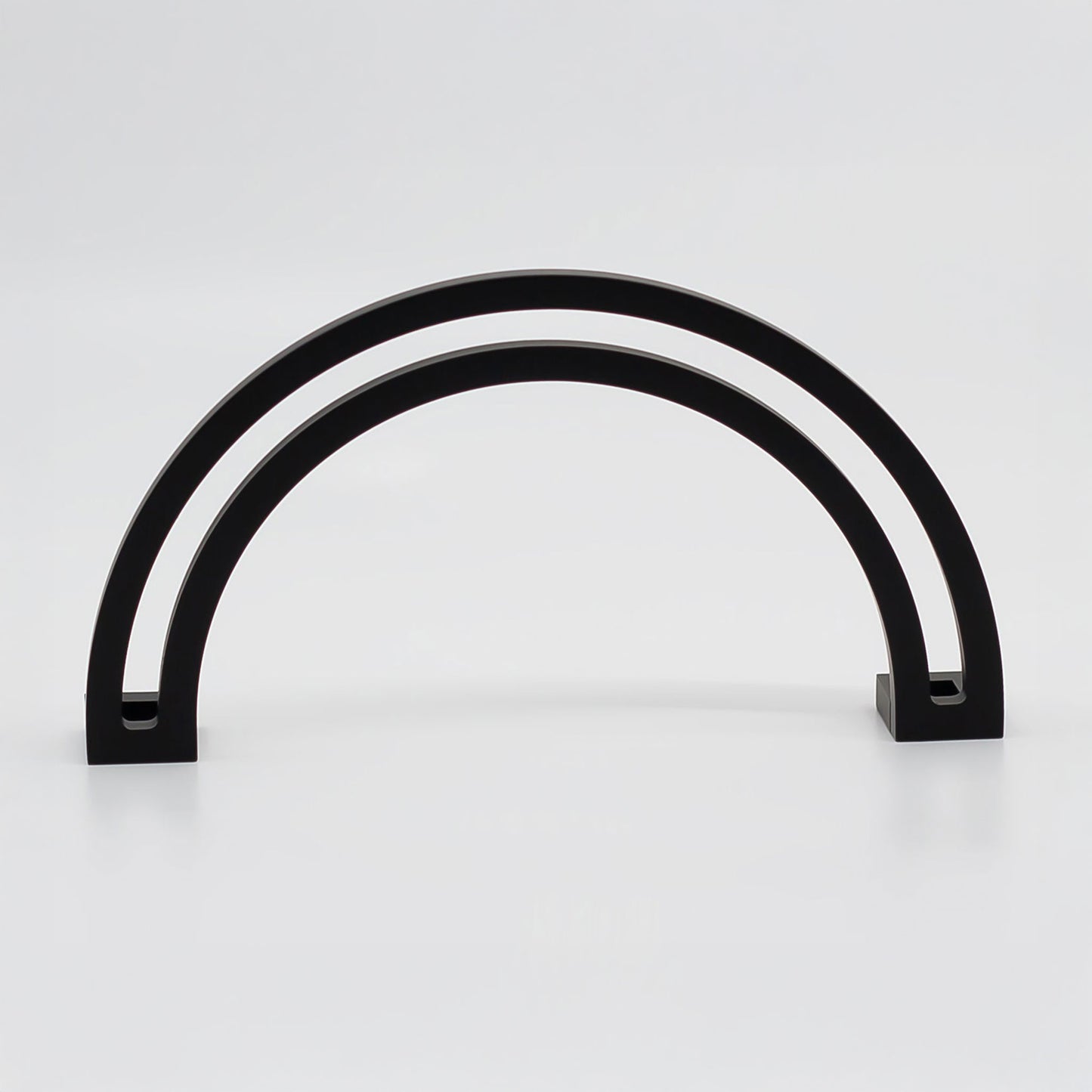 Arch shaped cabinet pull with cut out internal area on a grey background