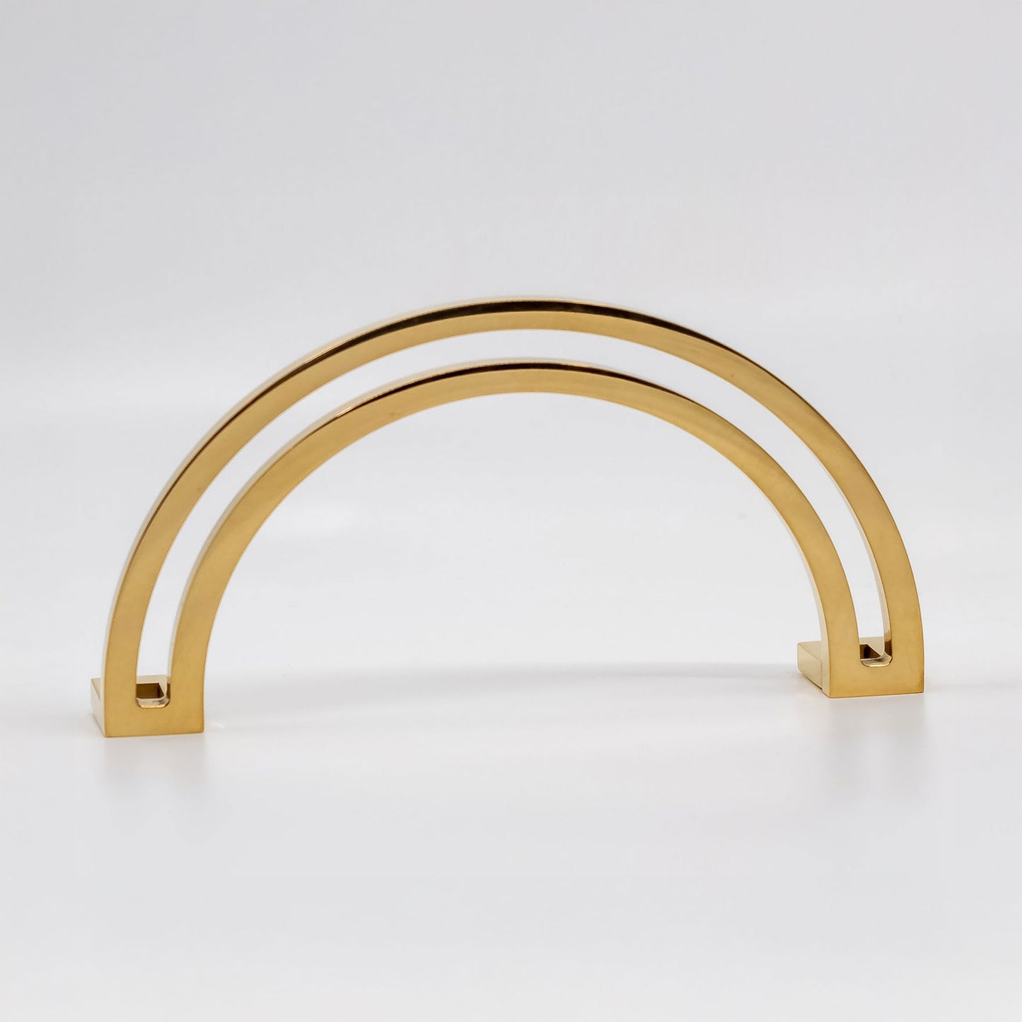 Arch shaped cabinet pull with cut out internal area on a grey background