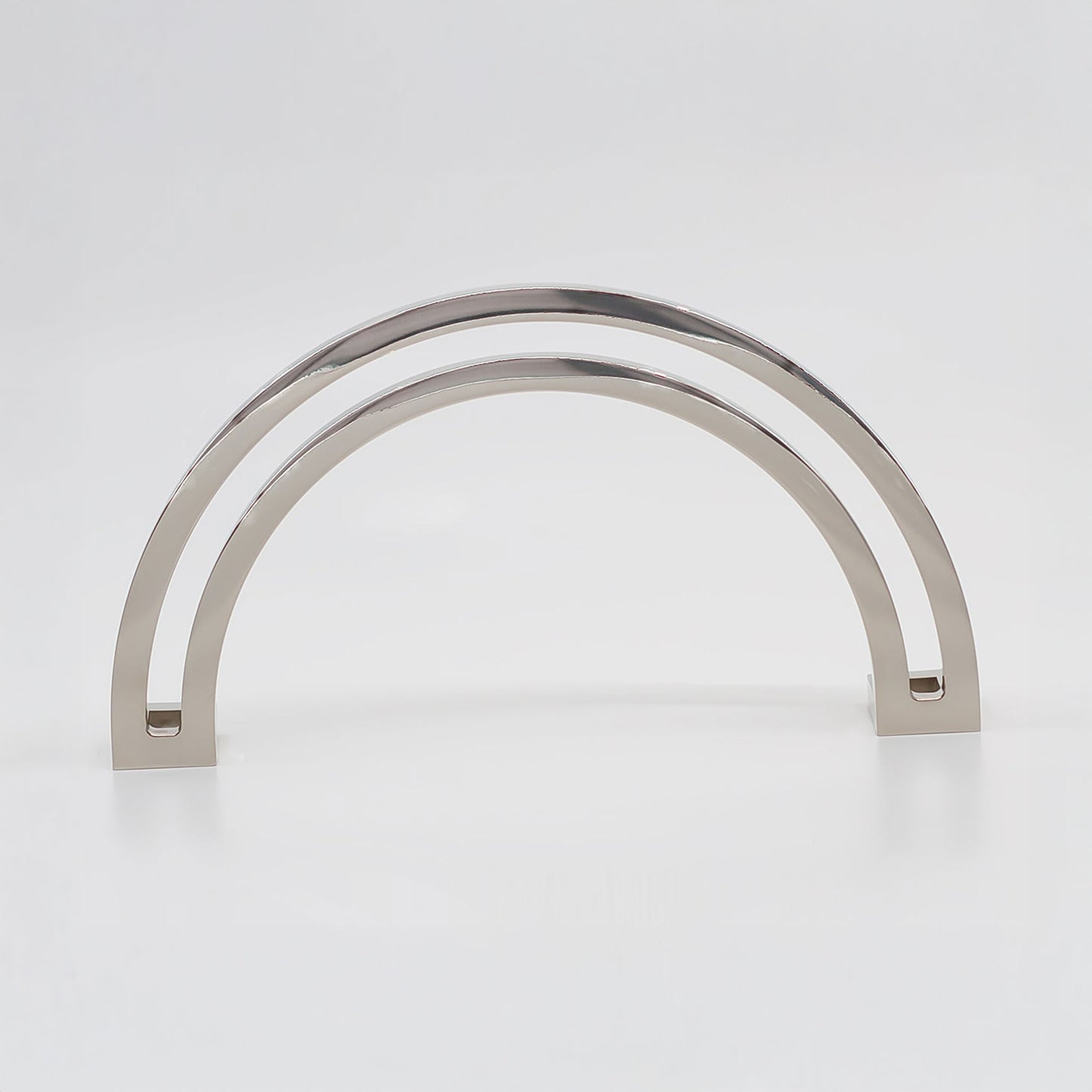 Arch shaped cabinet pull with cut out internal area on a grey background