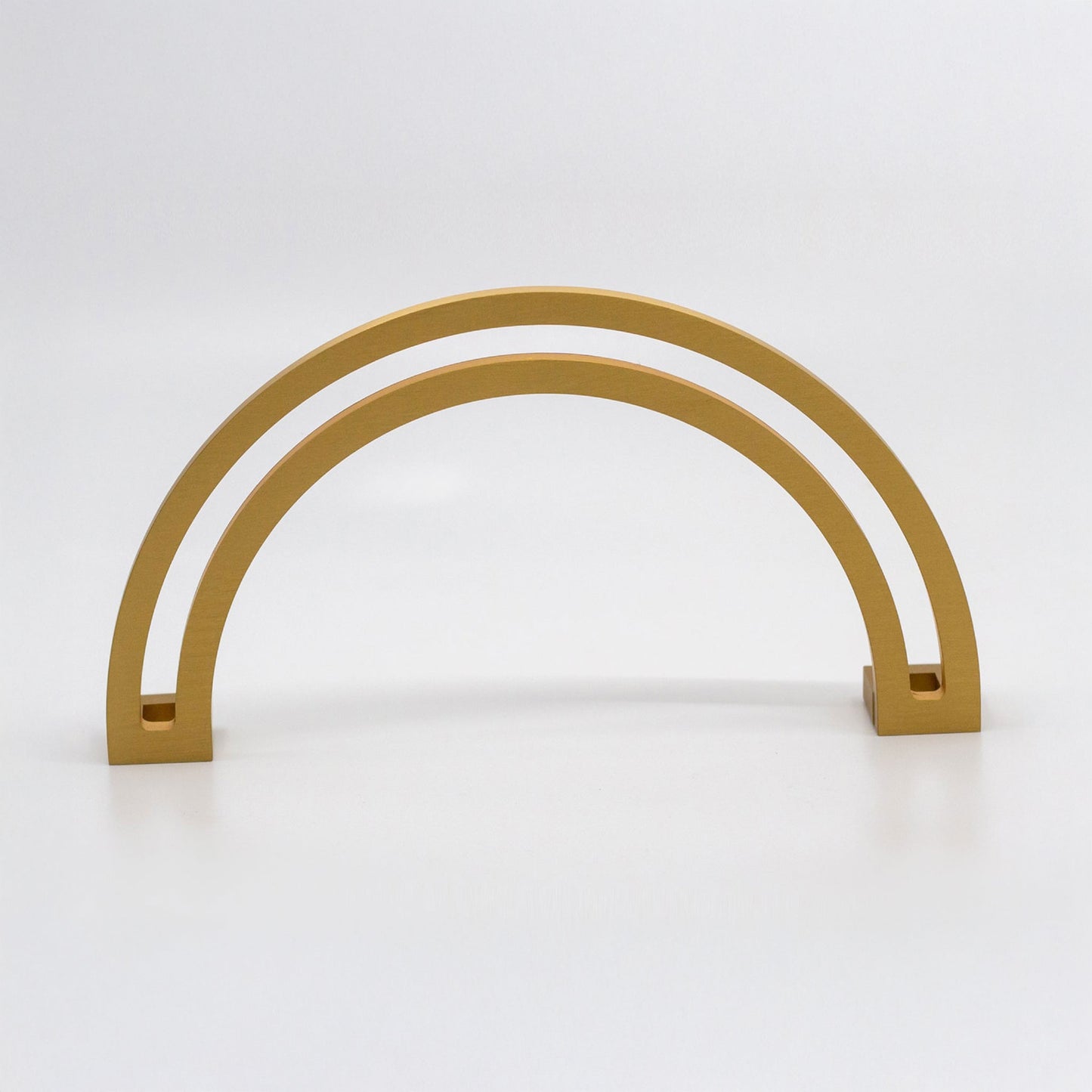 Arch shaped cabinet pull with cut out internal area on a grey background