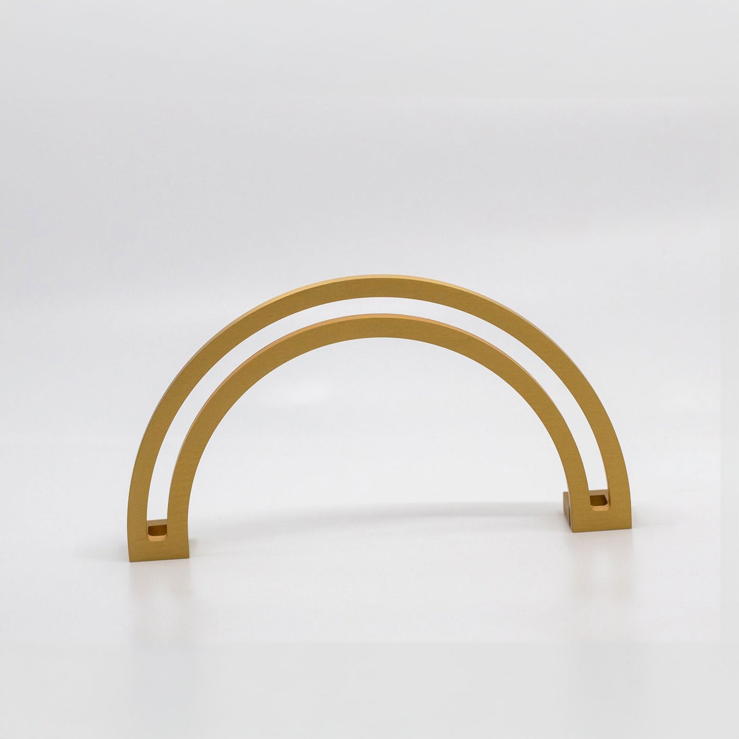 Arch shaped cabinet pull with cut out internal area on a grey background