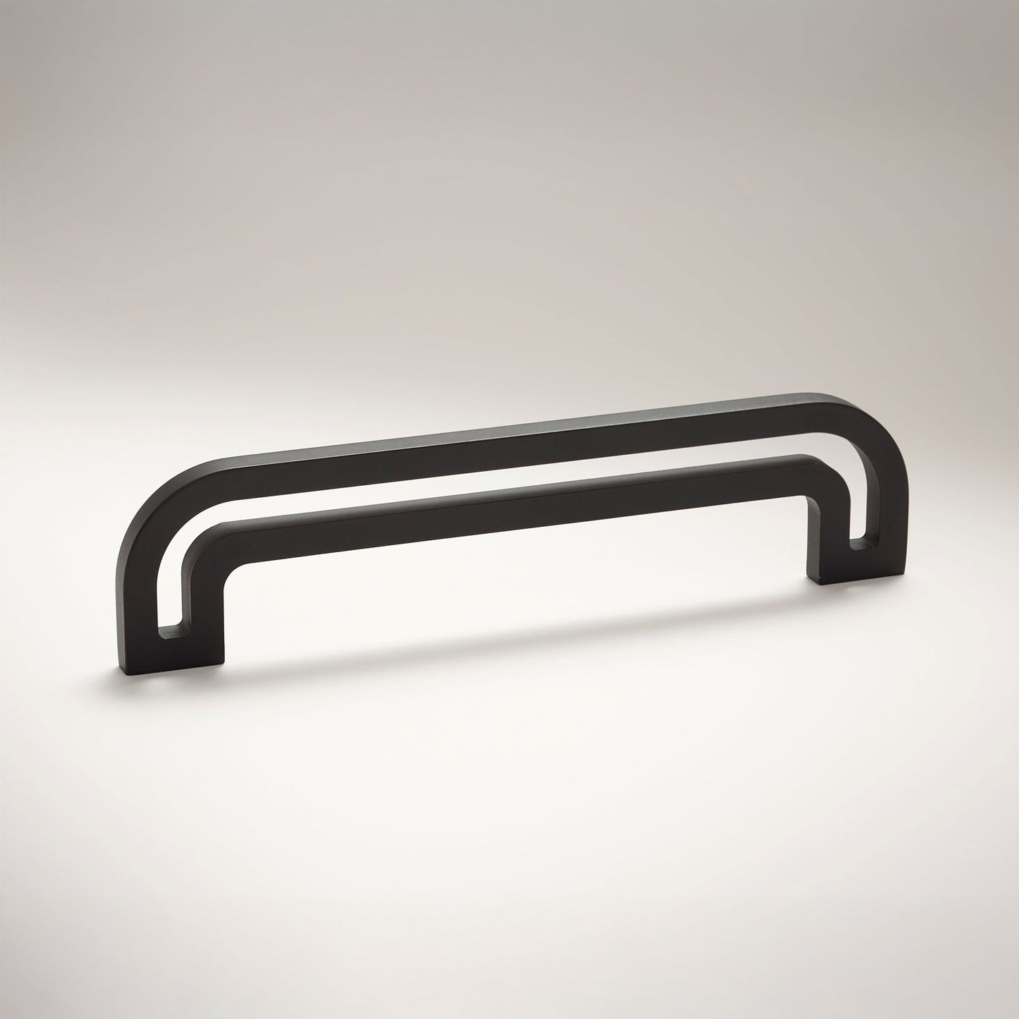Arch shaped linear cabinet pull with cut our internal area on a grey background