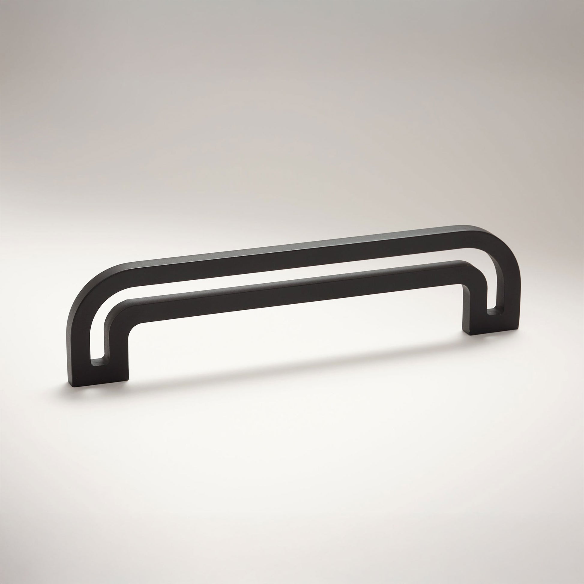 Arch shaped linear cabinet pull with cut our internal area on a grey background