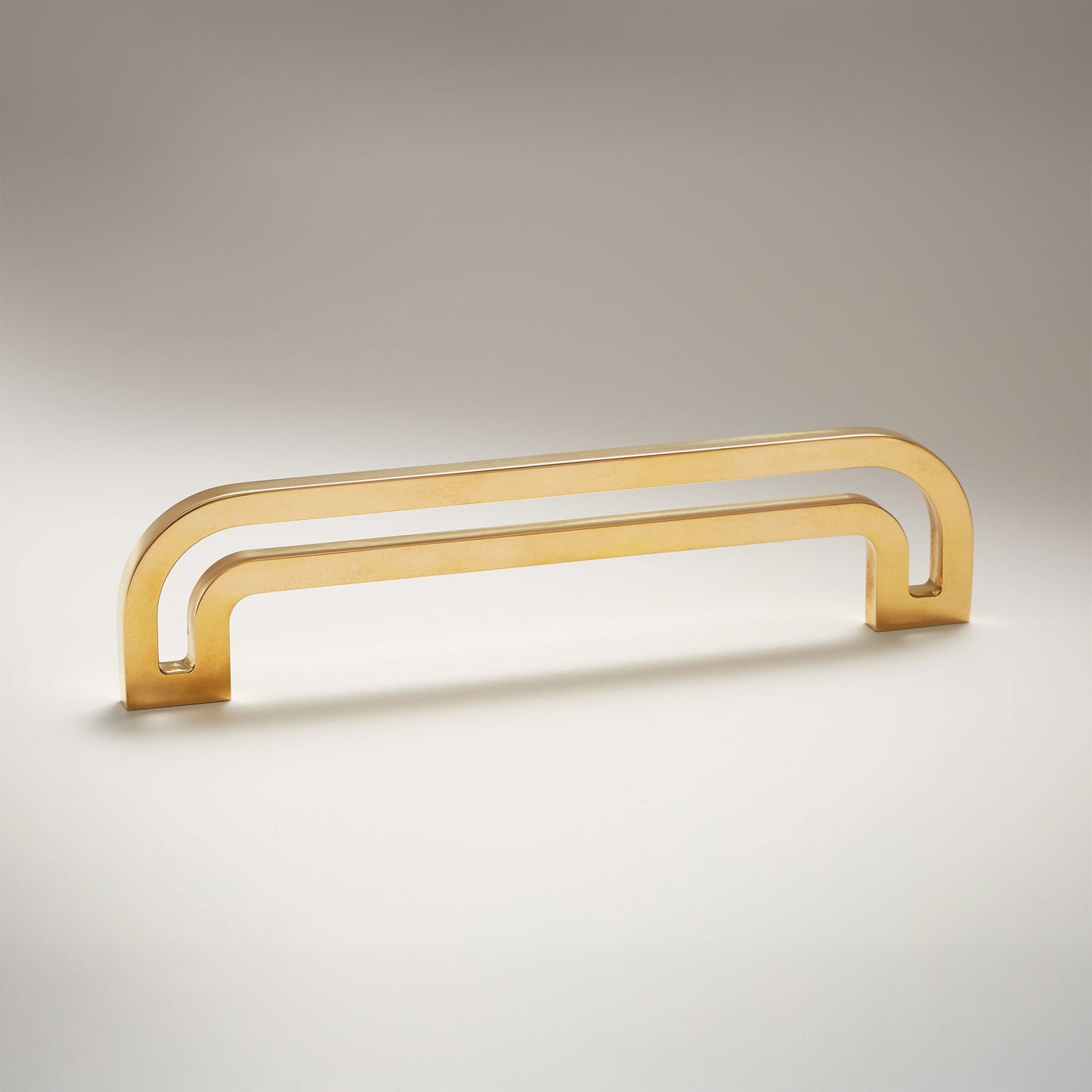 Arch shaped linear cabinet pull with cut our internal area on a grey background