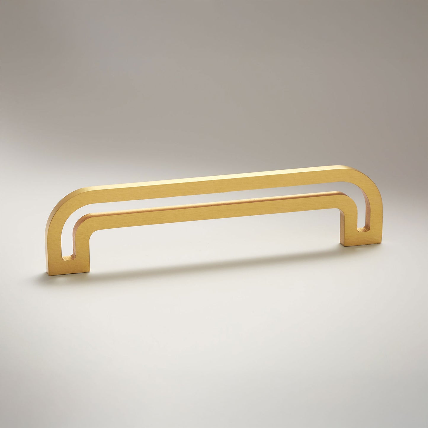 Arch shaped linear cabinet pull with cut our internal area on a grey background