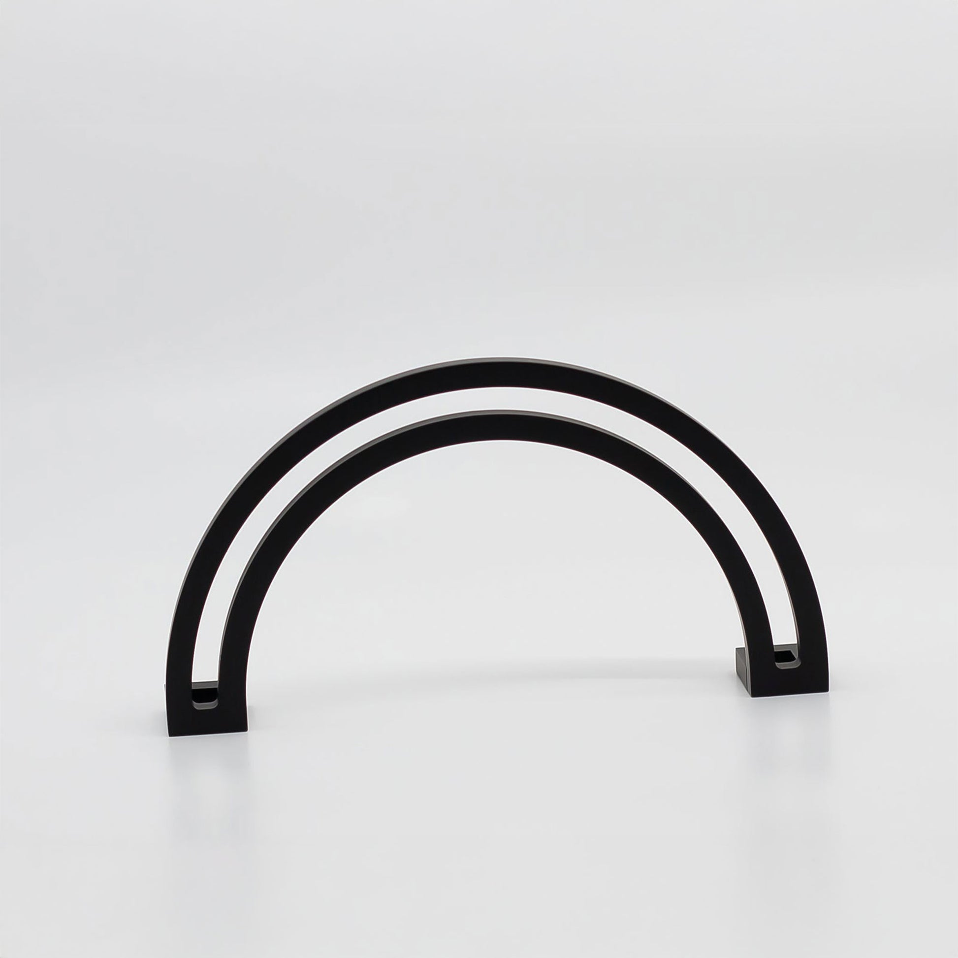 Arch shaped cabinet pull with cut out internal area on a grey background