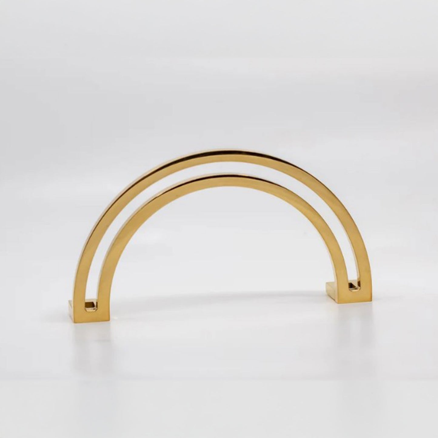 Arch shaped cabinet pull with cut out internal area on a grey background