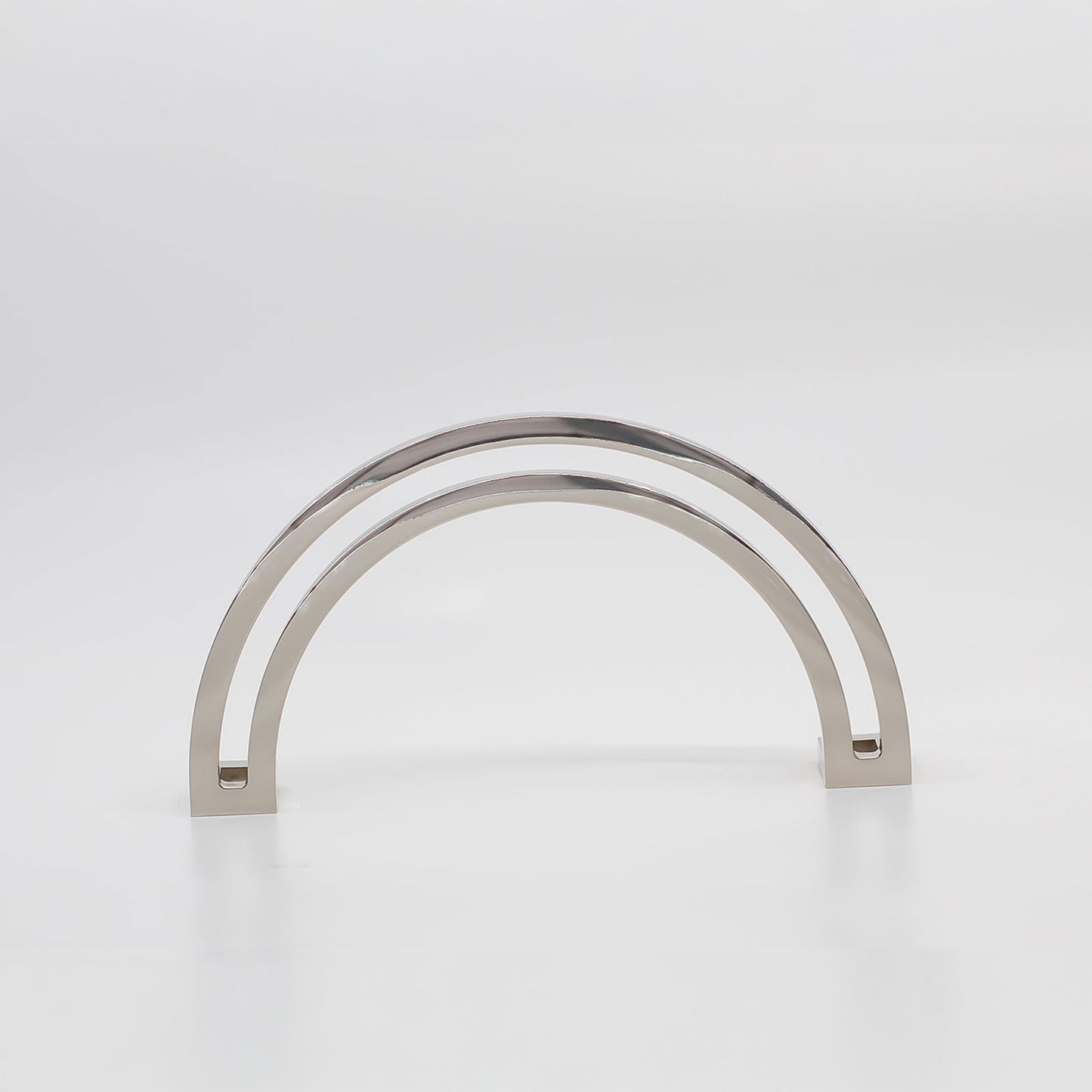 Arch shaped cabinet pull with cut out internal area on a grey background