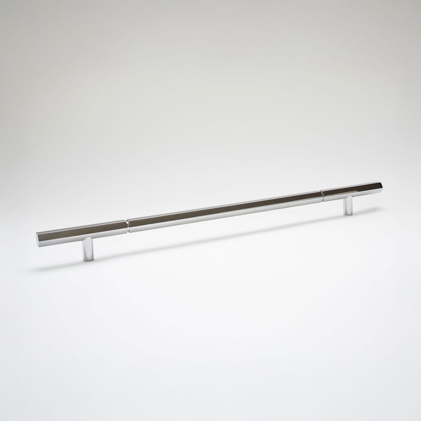 A modern hexagonal cabinet handle in polished chrome, featuring an extra long horizontal bar supported by two short cylindrical posts, shown on a light gray background.