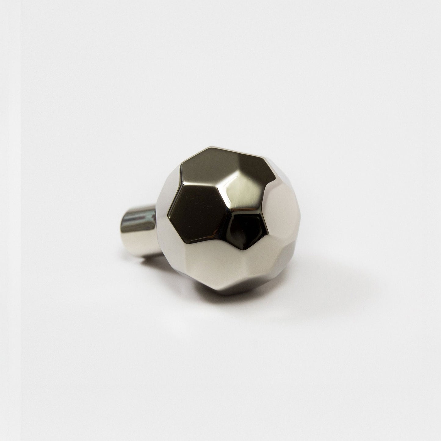 A modern hexagonal cabinet knob in polished nickel, with one short cylindrical post, shown on a light gray background.