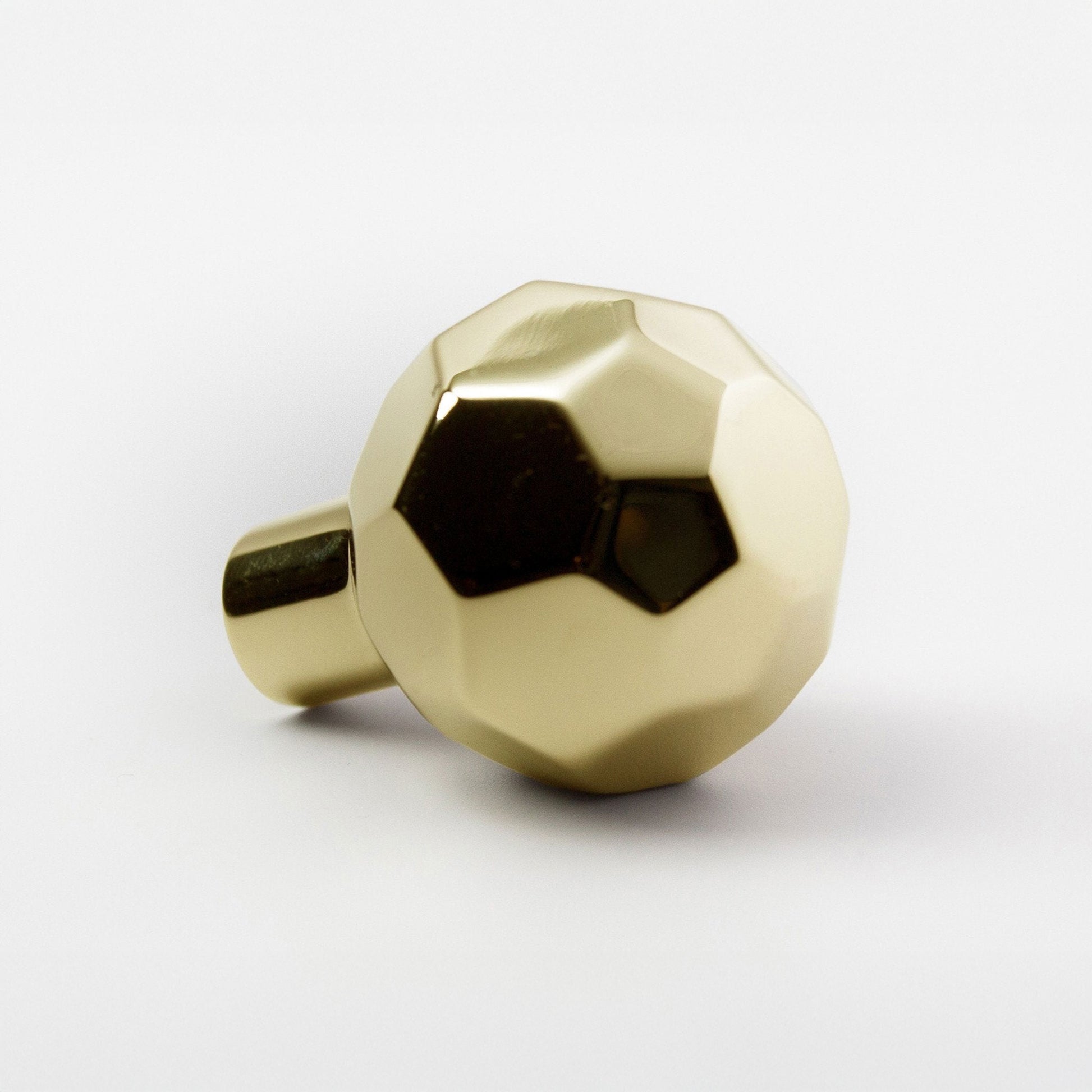 A metallic polished brass ball-shaped cabinet knob with a faceted design and a cylindrical mounting stem, shown on a clean white background.