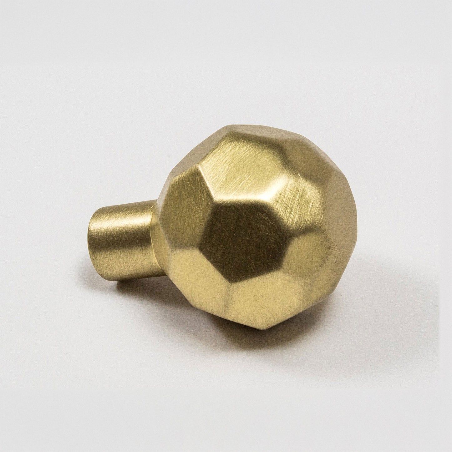 A metallic satin brass ball-shaped cabinet knob with a faceted design and a cylindrical mounting stem, shown on a clean white background.