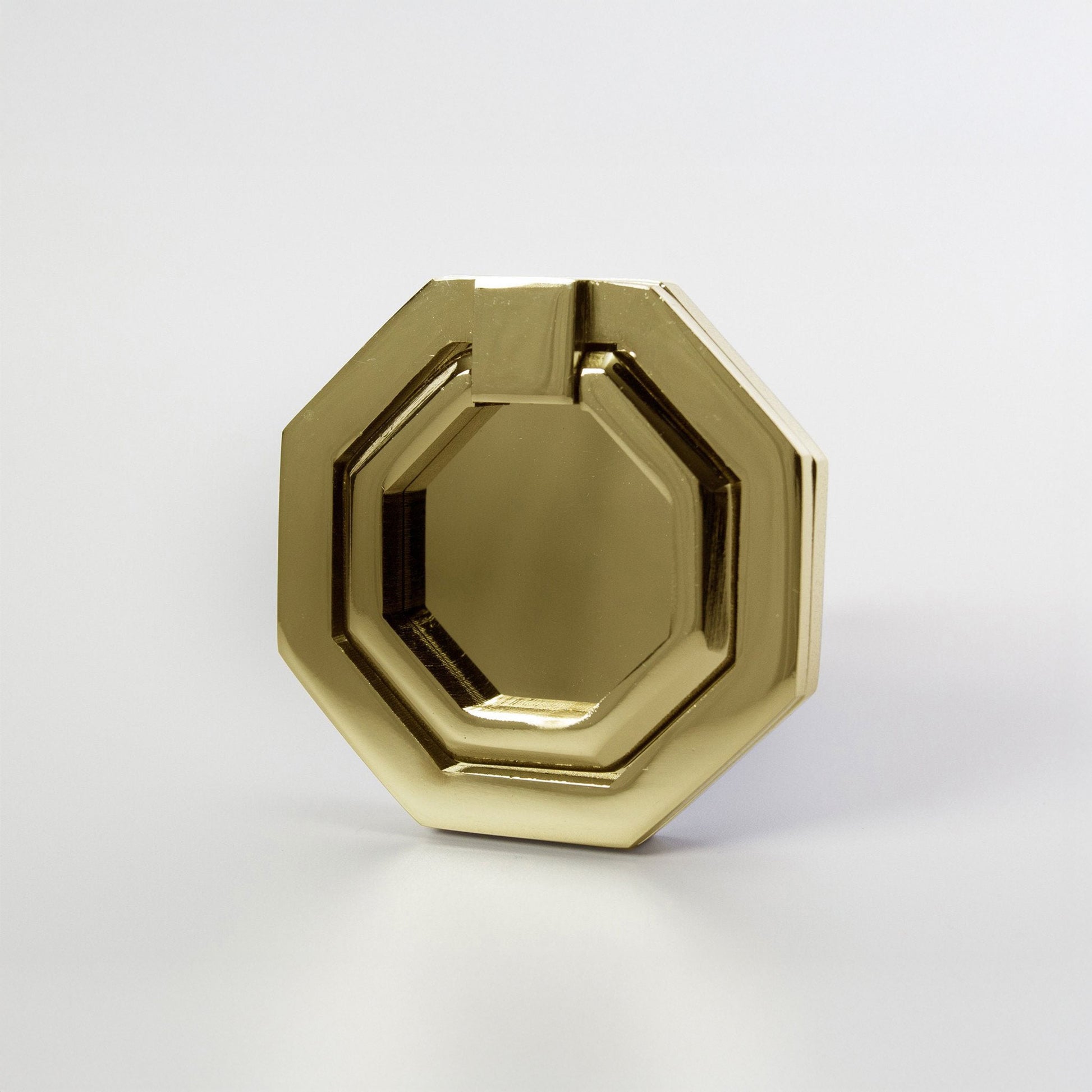 A gold-toned octagonal metal ring cabinet pull with a polished brass finish, photographed on a clean light gray background.