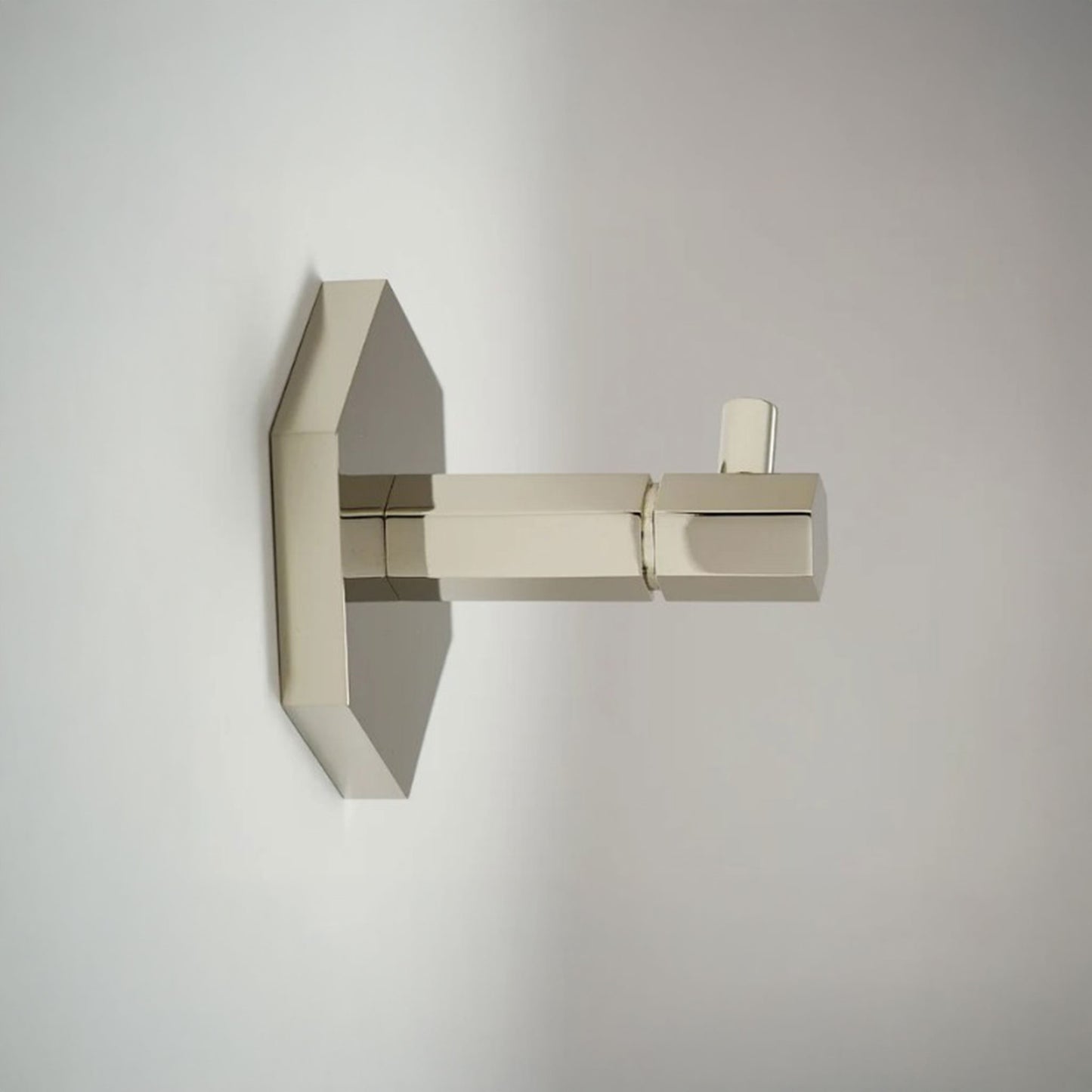 A modern wall-mounted towel hook  with a geometric, angular design in a brushed nickel finish, shown against a neutral light gray background.