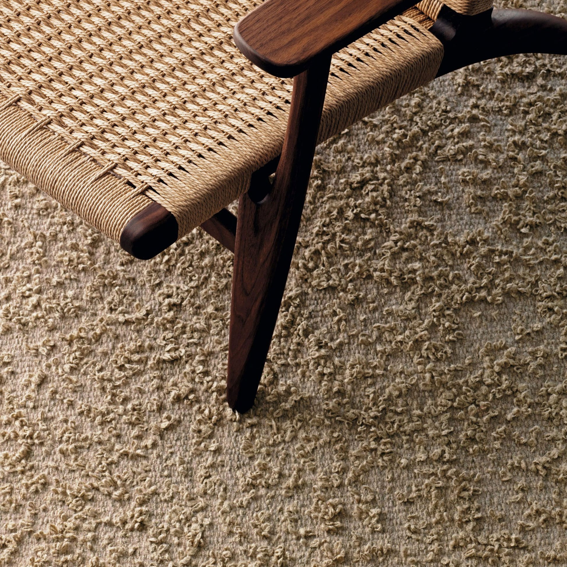 Folia rug style in taupe colored intermittent boucle weave with a midcentury chair