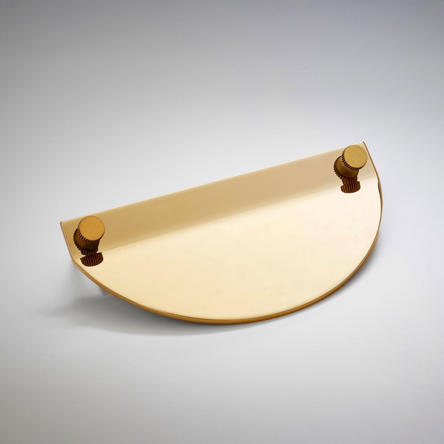 A modern semi-circular cabinet pull in a gold polished brass finish, featuring two small round gold-toned details on the top edges, on a neutral background.