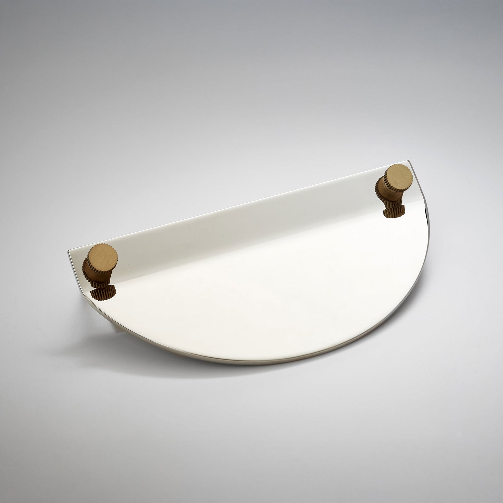 A modern semi-circular metal cabinet pull in a polished nickel finish, featuring two small round gold-toned details on the top edges, on a neutral background.