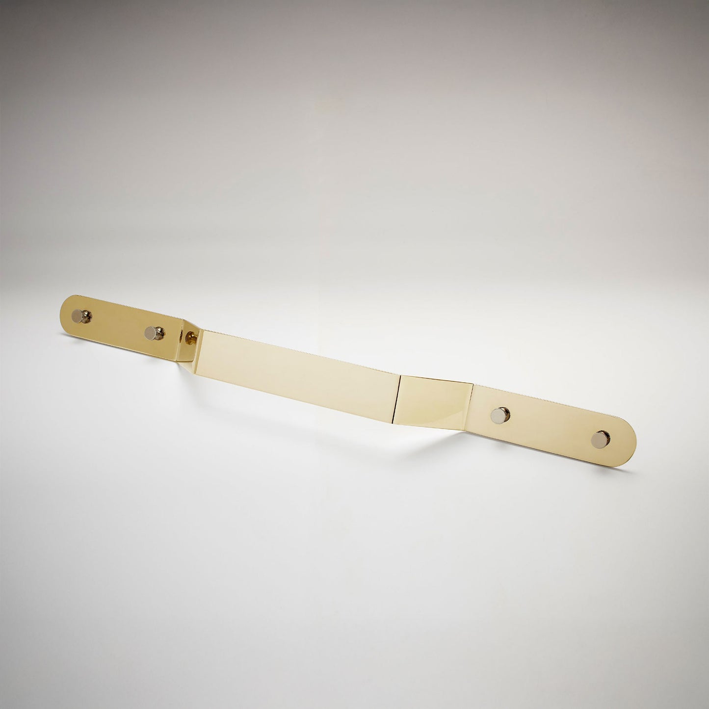 A minimalist, long, polished unlaquered brass metal cabinet pull handle with two mounting holes, shown on a white background.