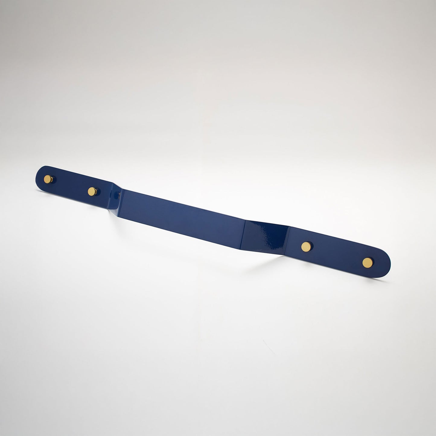 A shiny navy powder coated, extra long bent rectangular metal cabinet pull handle with two small, round, brass details on each corner photographed on a white background.