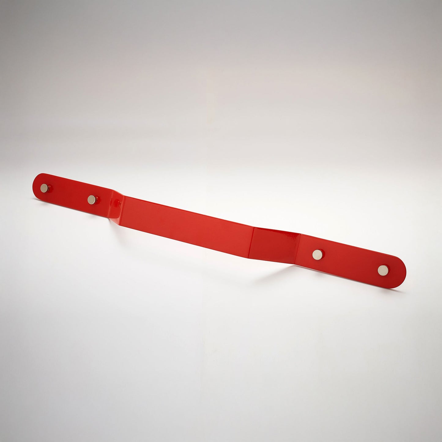 A shiny red powder coated, extra long bent rectangular metal cabinet pull handle with two small, round, brass details on each corner photographed on a white background.