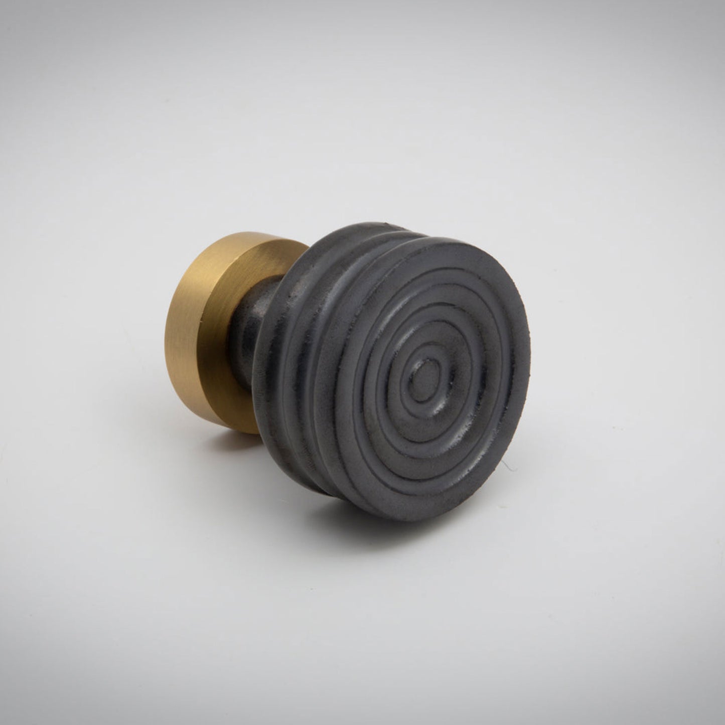 Small black ceramic cabinet knob with gold accent on a white background.
