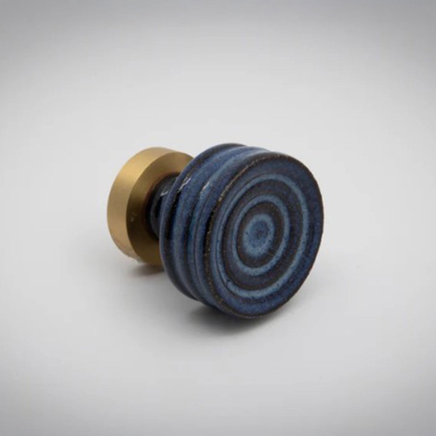 Small blue ceramic cabinet knob with gold accent on a white background.