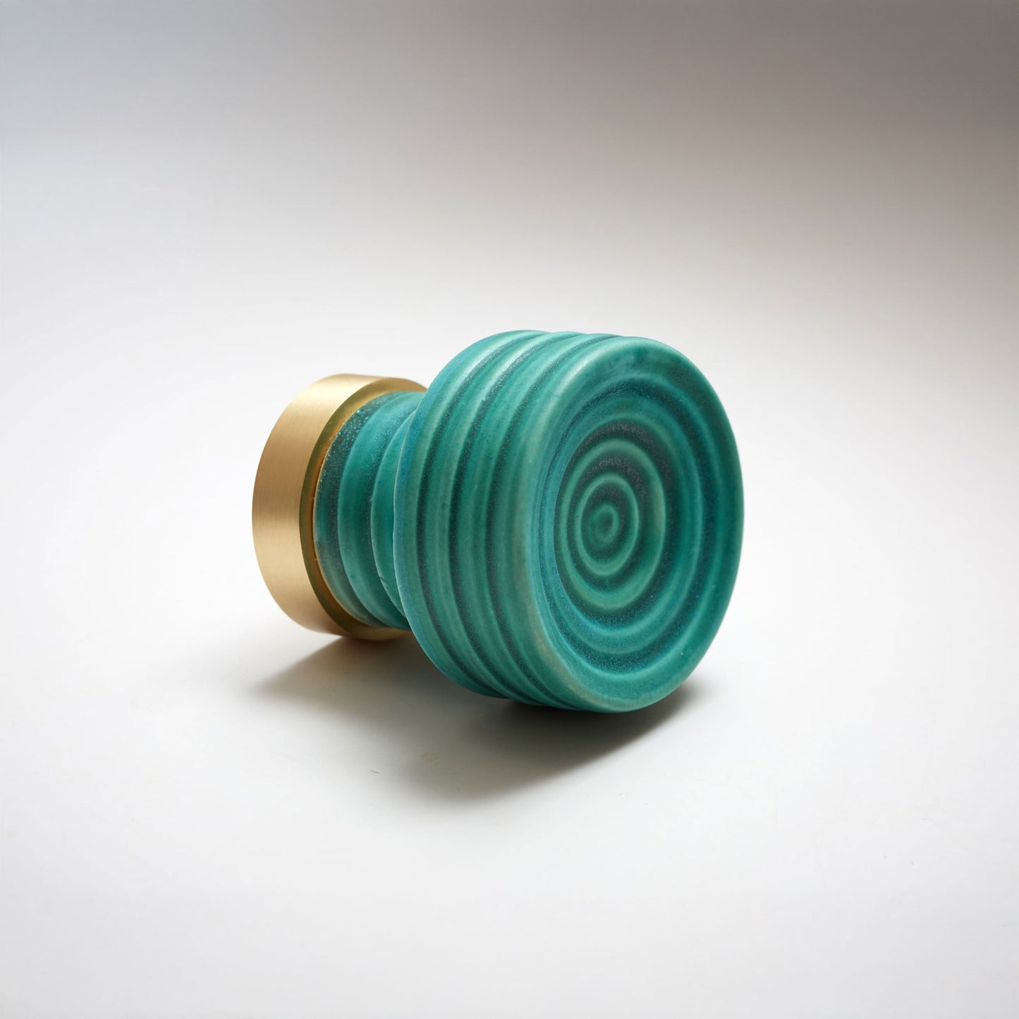 Small ceramic teal cabinet knob with gold accent on a white background.