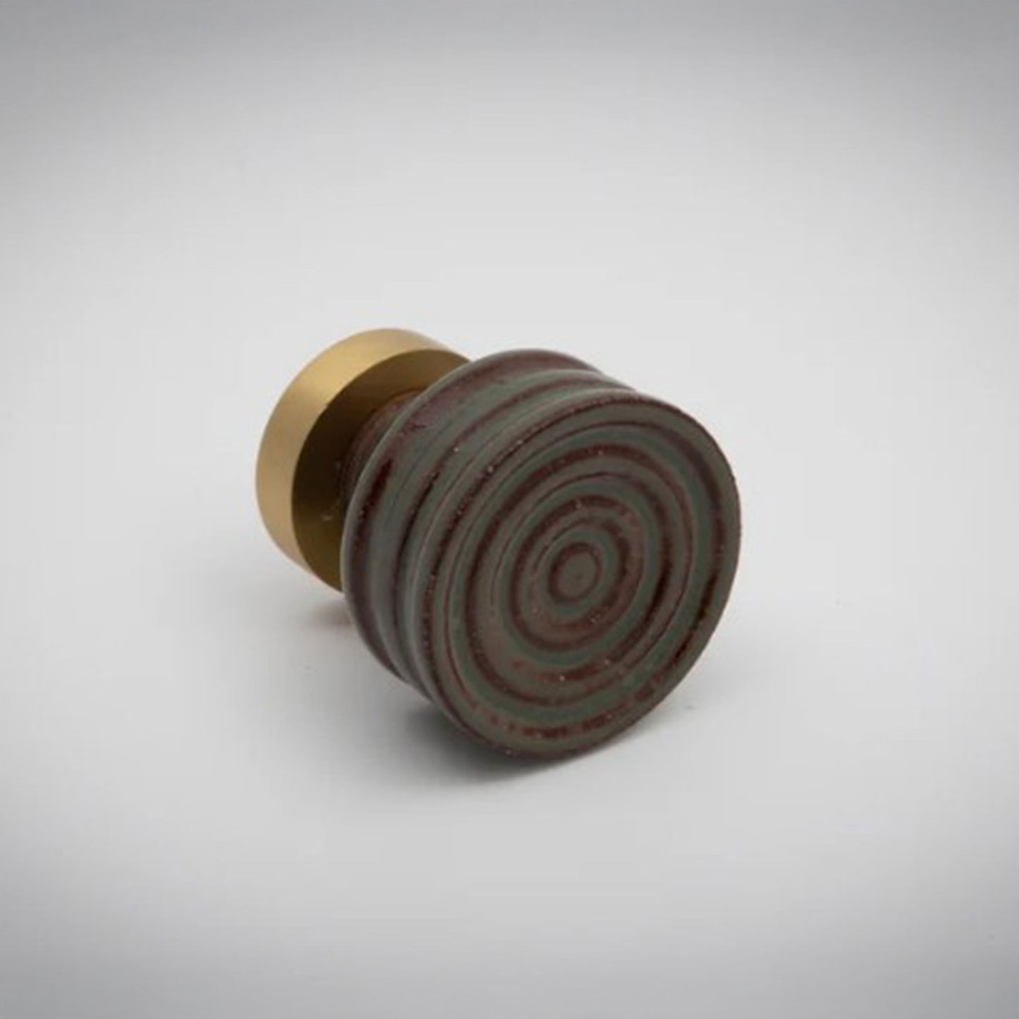 Small sage green and terracotta ceramic cabinet knob with gold accent on a white background.