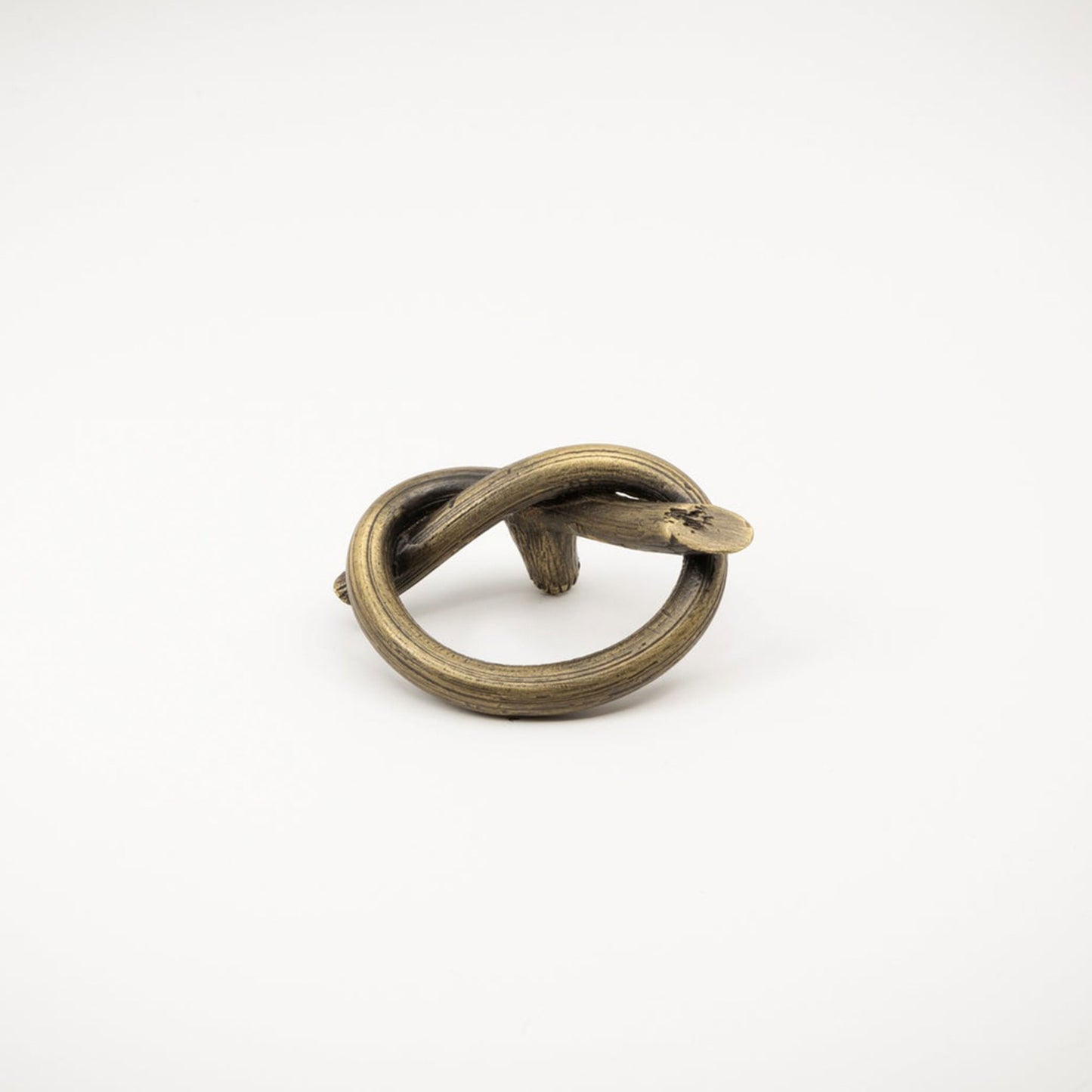 A rustic bronze metal ring with a twisted knot design, photographed on a white background.