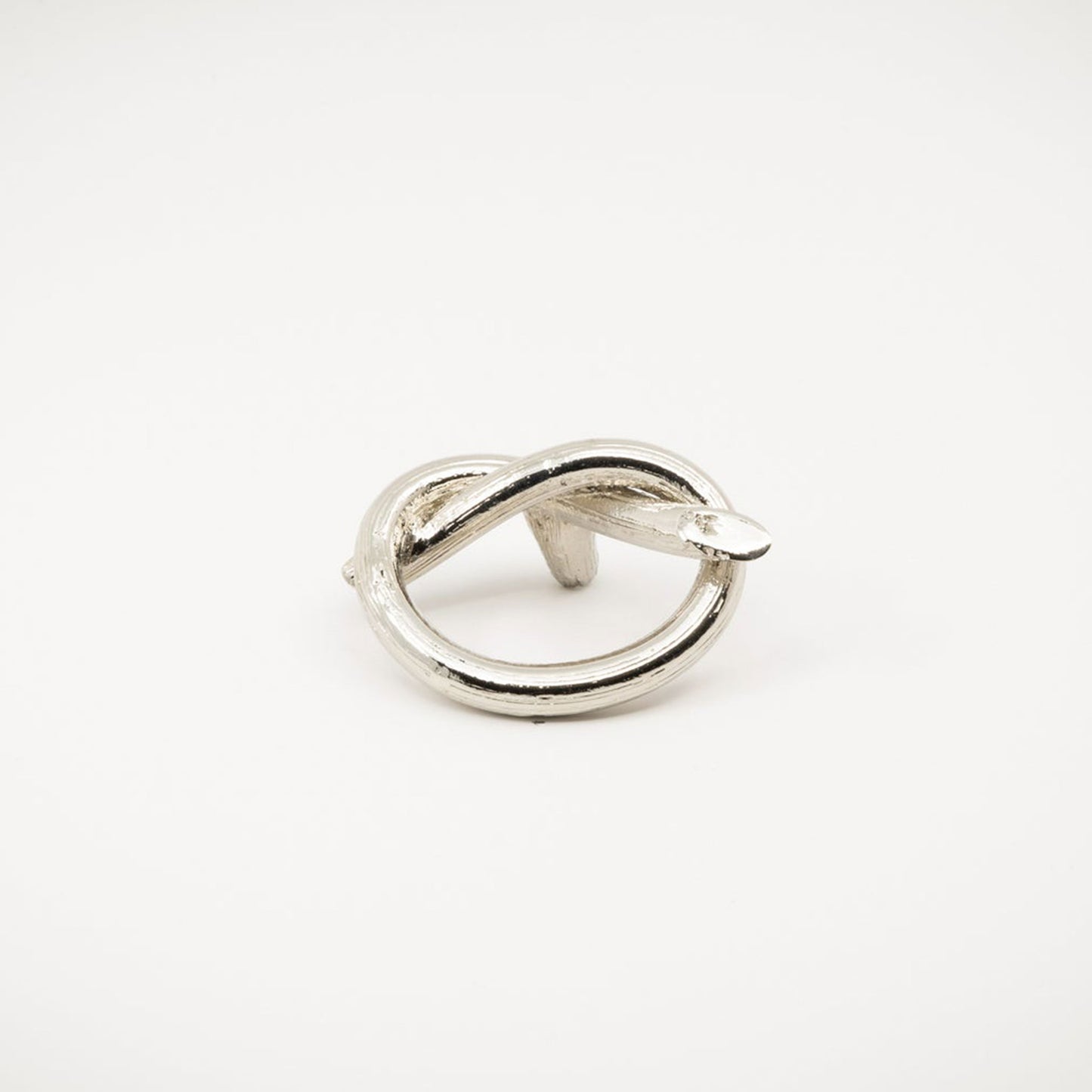 A polished nickel metal ring with a twisted knot design, photographed on a white background.