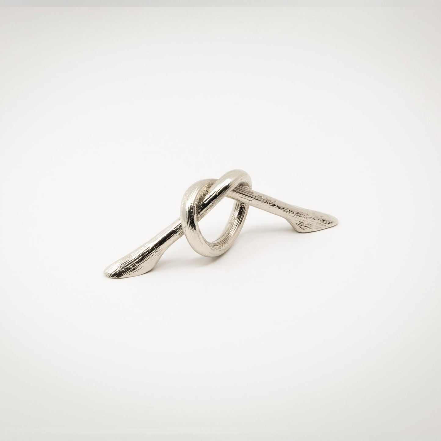 A small silver-toned polished nickel metal hardware piece with a looped, knot-like design and two angled ends, photographed on a white background.