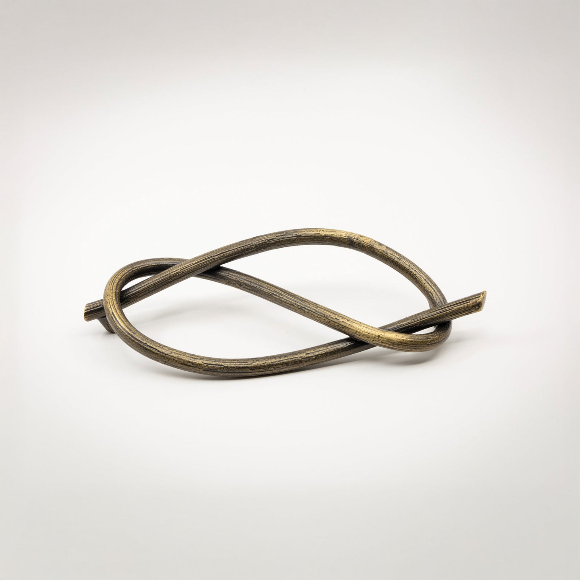 A twisted metal sculptural cabinet pull with a textured bronze finish, photographed on a light gray background.
