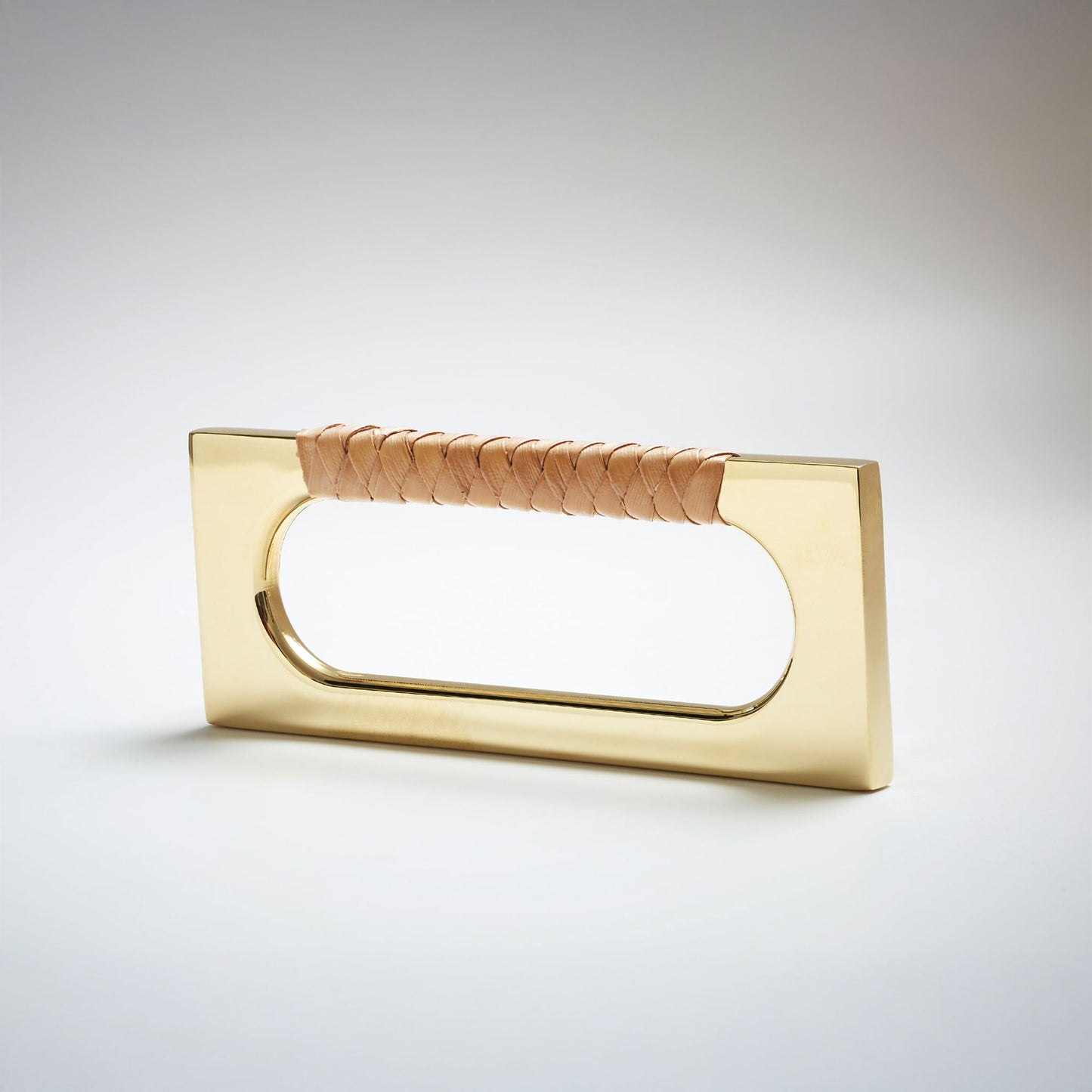 A modern rectangular cabinet pull handle with a polished brass finish and a textured woven brown leather handle, shown on a white background.
