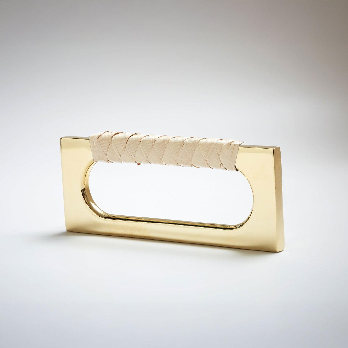 A modern rectangular cabinet pull handle with a shiny natural brass finish and a textured woven light tan leather handle, shown on a white background.