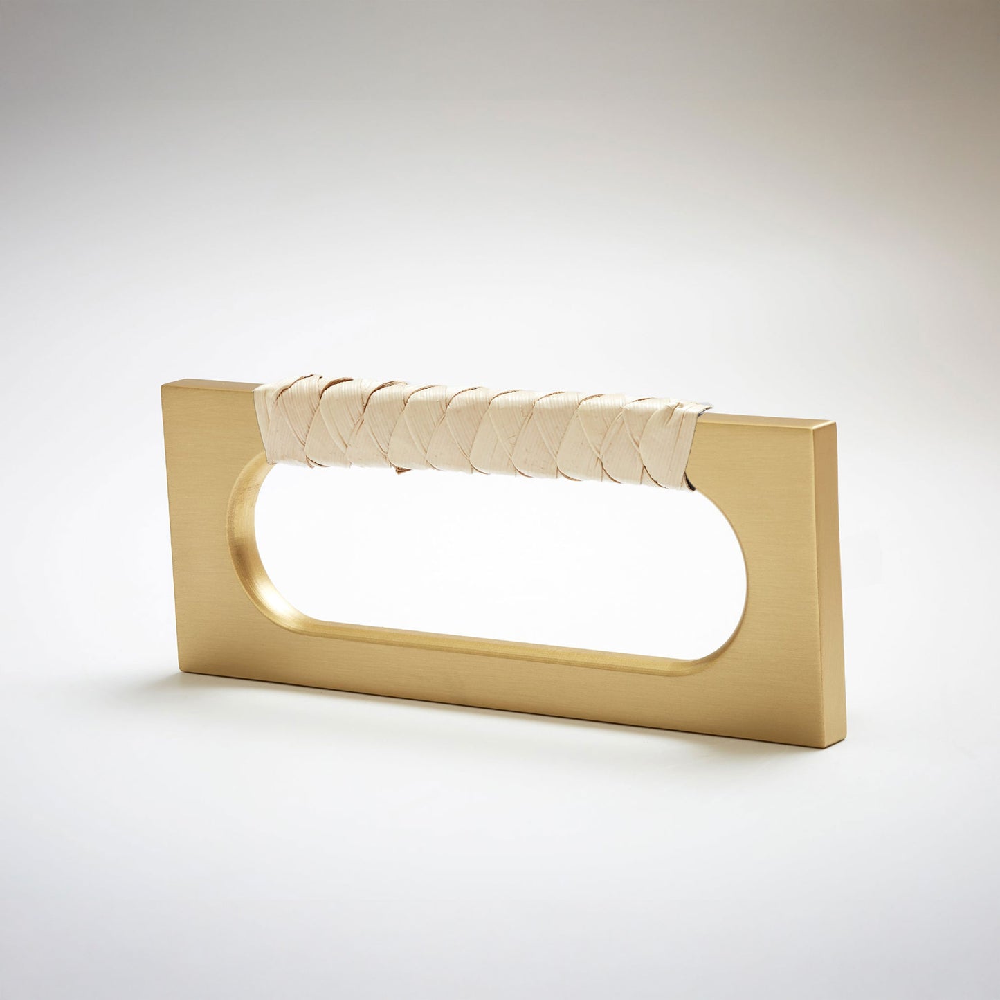 A modern rectangular cabinet pull handle with a satin brass finish and a textured woven light tan leather handle, shown on a white background.