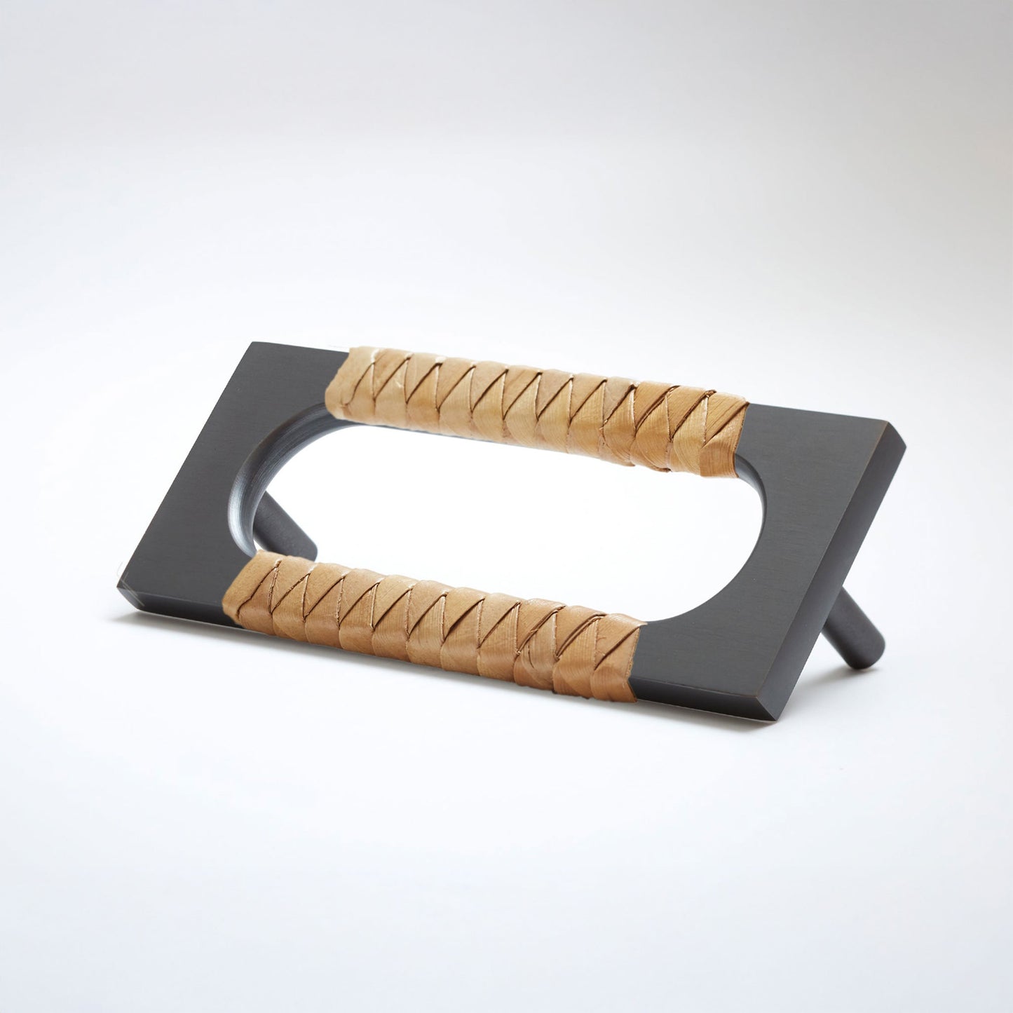 A modern dark oil-rubbed bronze metal cabinet pull handle with an oval cutout, wrapped with a natural beige screwpine leaf reed,  shown on a white background.