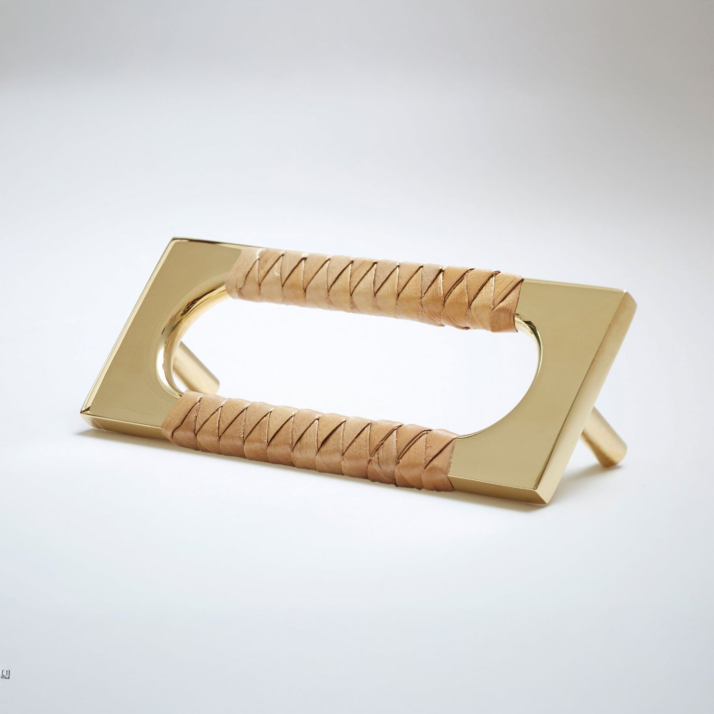 A modern natural bronze metal cabinet pull handle with an oval cutout, wrapped with a natural beige screwpine leaf reed,  shown on a white background.