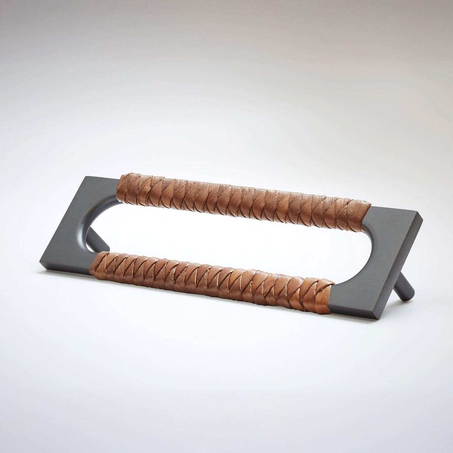 A modern metal cabinet pull handle with a dark gray rectangular frame and two wrapped brown leather grips, shown on a light gray background.