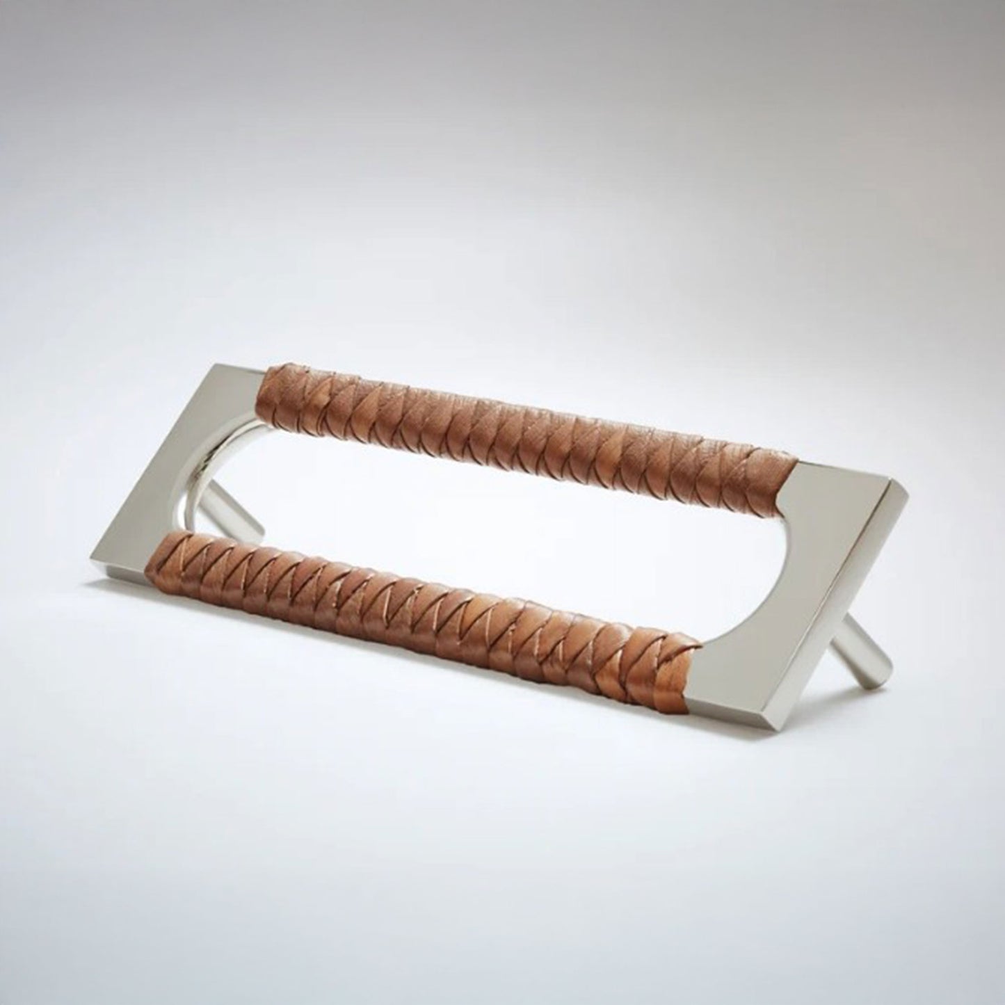 A modern metal cabinet pull handle with a brushed silver finish and brown braided leather wrapping on both sides, shown on a light gray studio background.