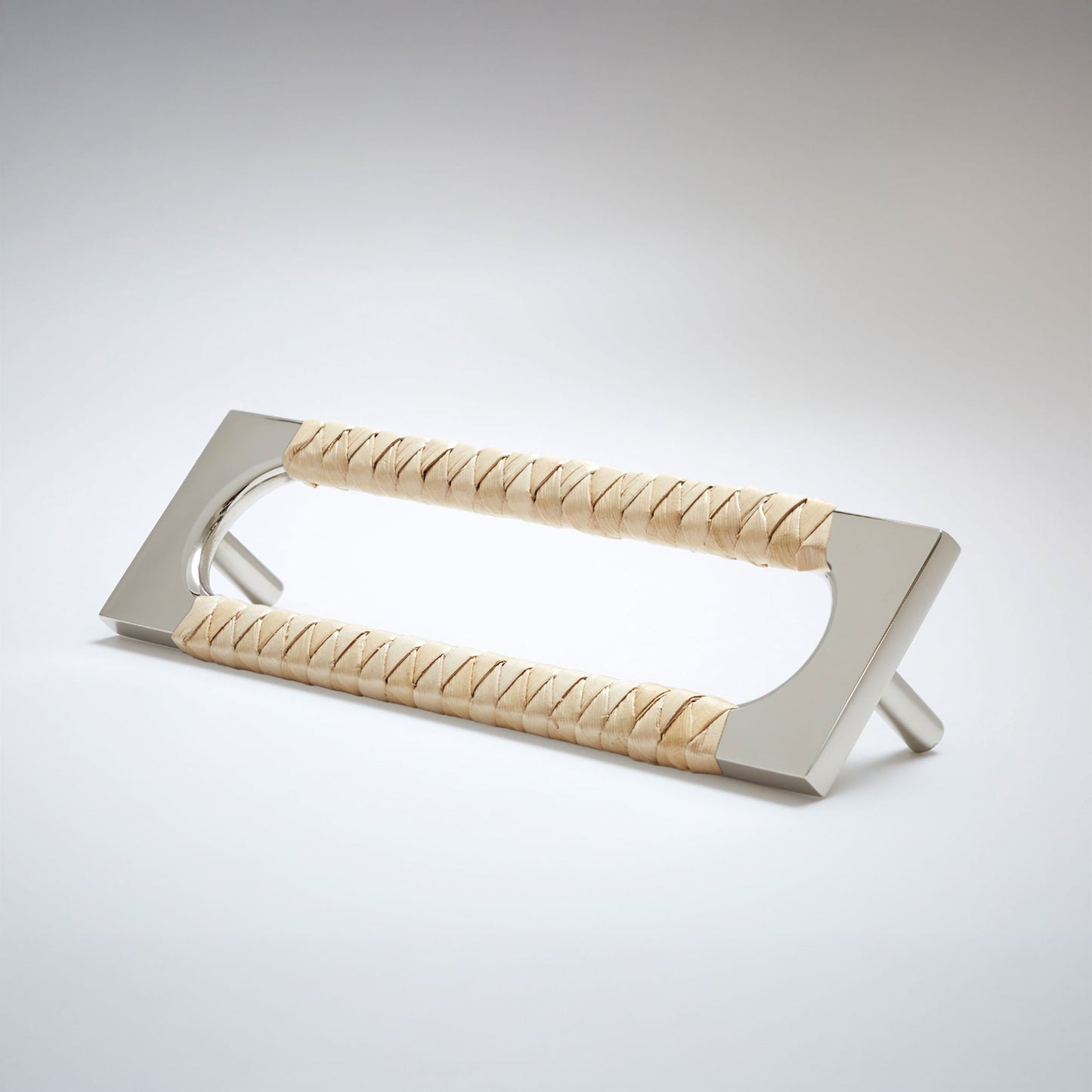 A modern metal cabinet pull handle with a brushed silver finish and brown braided leather wrapping on both sides, shown on a light gray studio background.