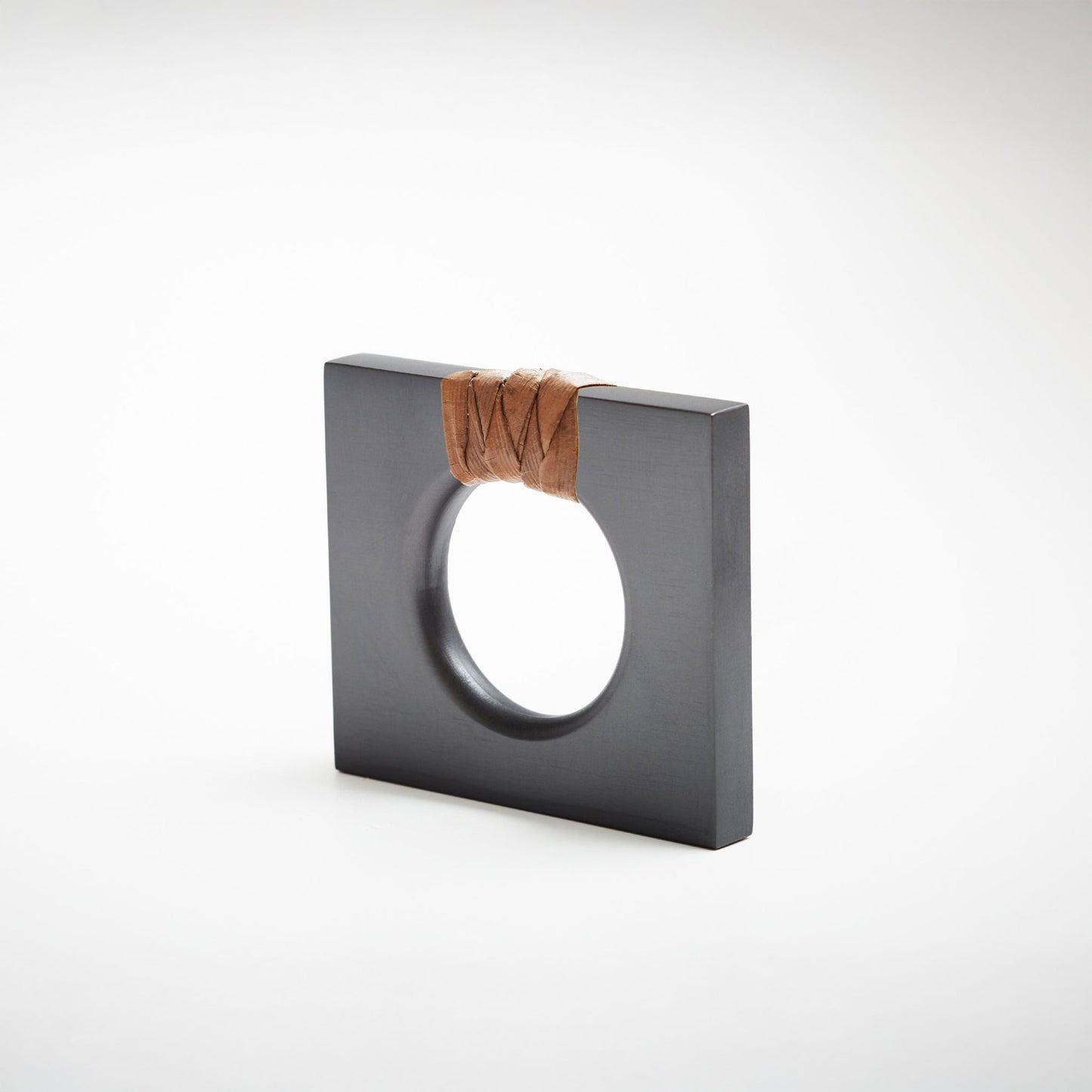 A petite dark gray square cabinet knob with a circular cutout, featuring a dark natural brown woven cord wrapped around the top edge, set against a white background. 