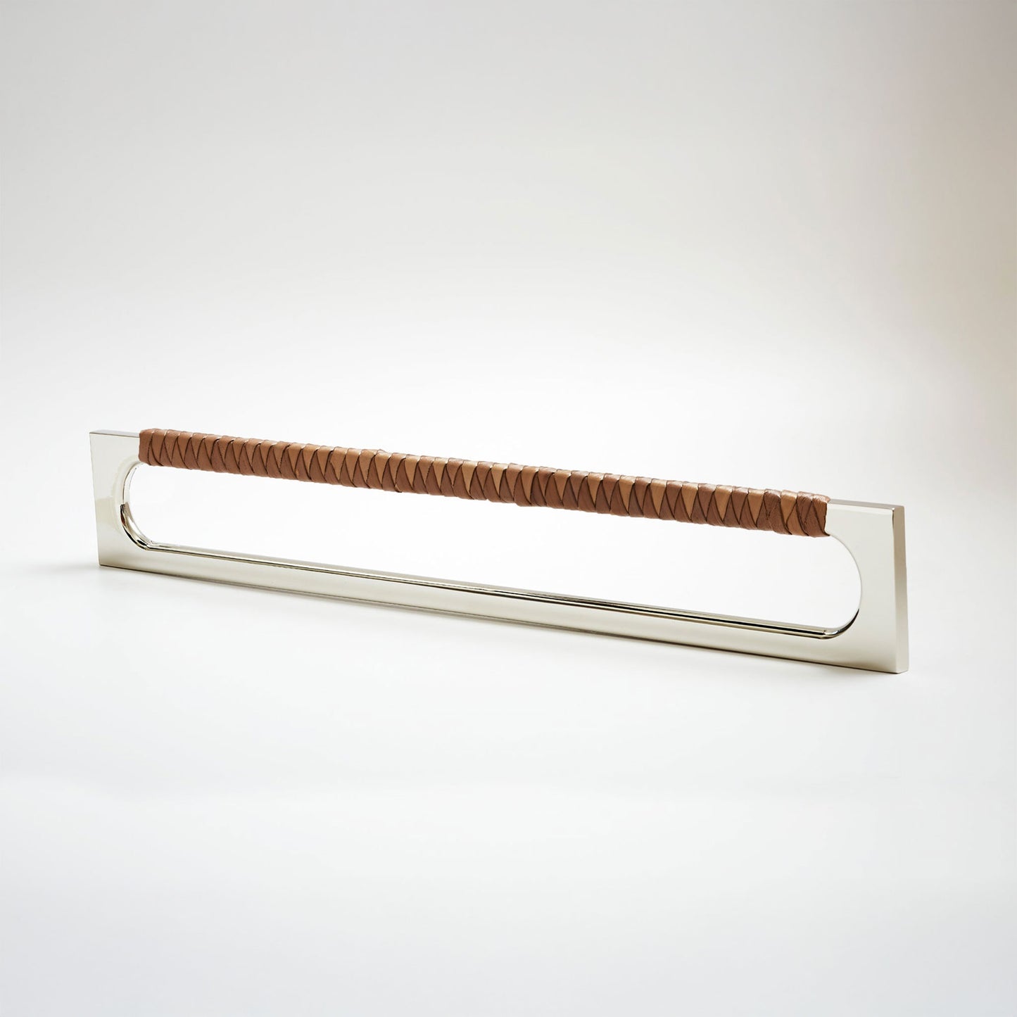 A modern long rectangular cabinet pull handle with a polished nickel metal frame with an oval shaped-cutout and a brown leather woven grip, shown on a white background.