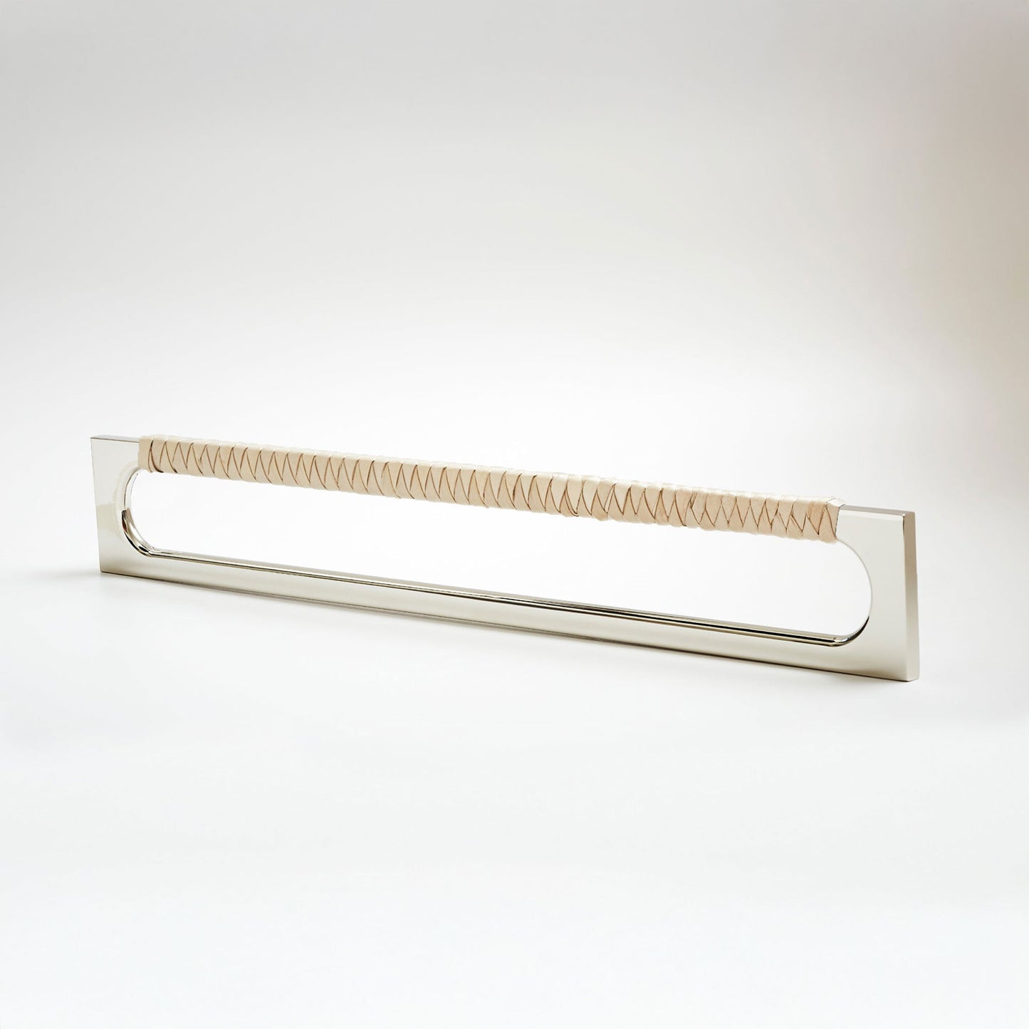 A modern long rectangular cabinet pull handle with a polished nickel metal frame with an oval shaped-cutout and a light tan leather woven grip, shown on a white background.