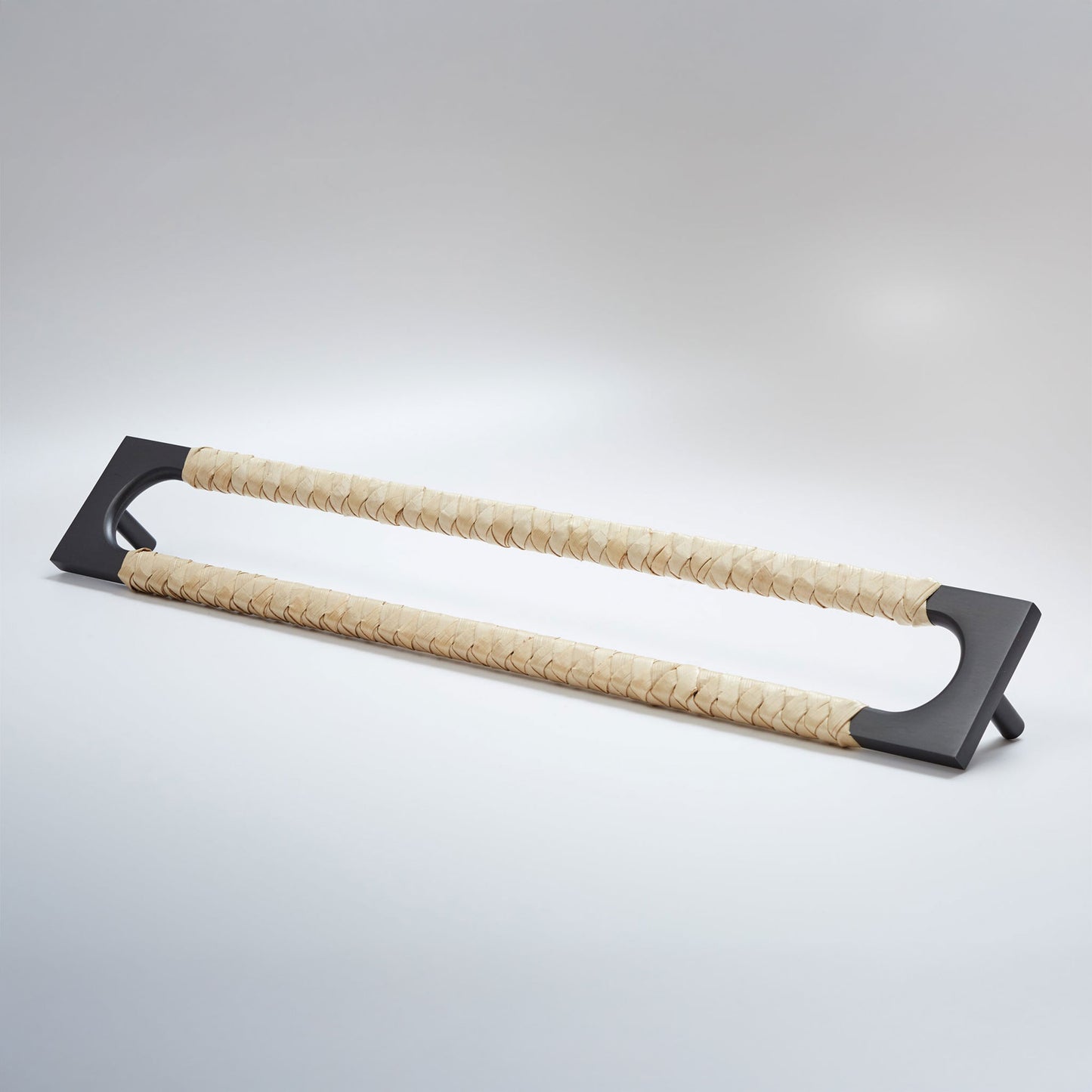A modern long rectangular cabinet pull handle with a dark oil-rubbed bronze metal frame with an oval shaped-cutout and a light tan leather woven grip, shown on a white background.