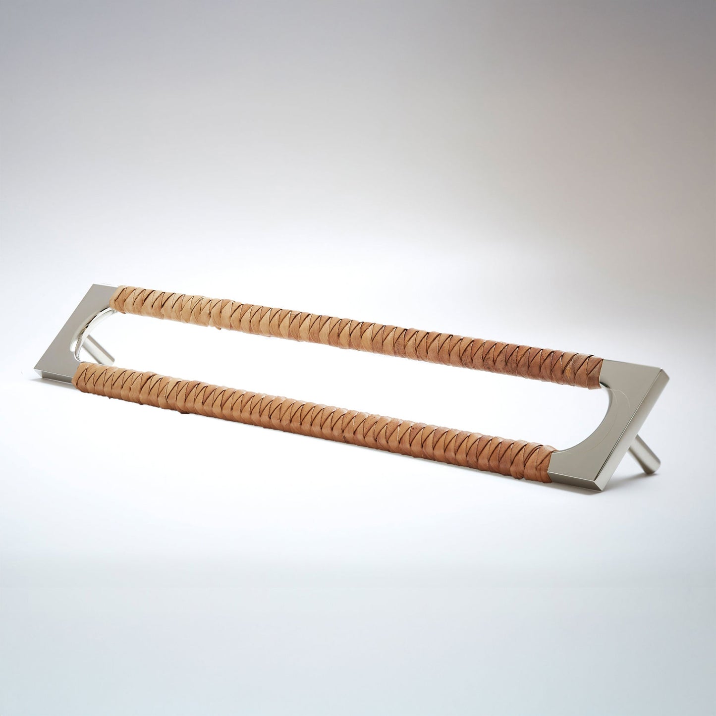 A modern long rectangular cabinet pull handle with a polished natural brass metal frame with an oval shaped-cutout and a brown leather woven grip, shown on a white background.
