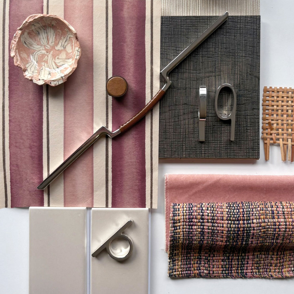 a design flat lay with various textured fabrics and including cognac colored leather knobs and pulls along side silver colored loop shaped pulls on a white background.