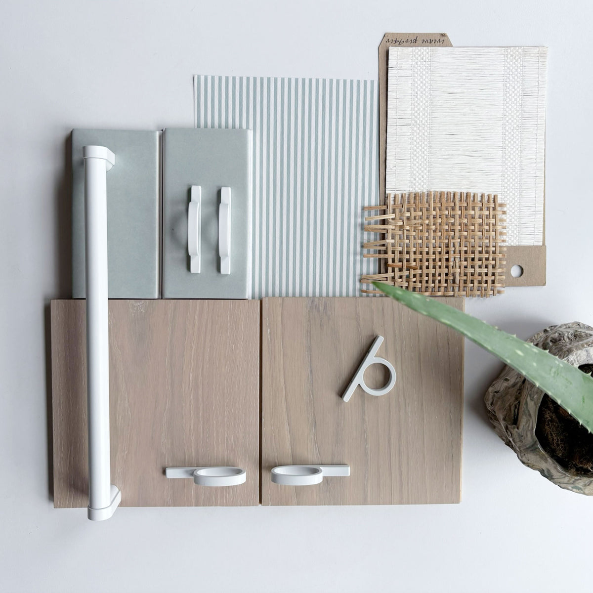 a design flat lay with various textured fabrics and wood finishes and including matte white knobs and pulls along side pale sage colored ceramic tiles on a white background.
