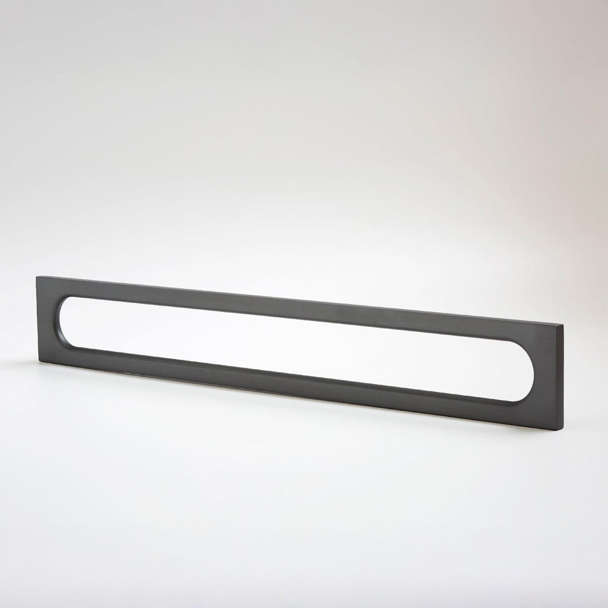 A long, narrow rectangular metak cabinet pull with a rounded rectangular cutout in the center, photographed on a clean light gray studio background.