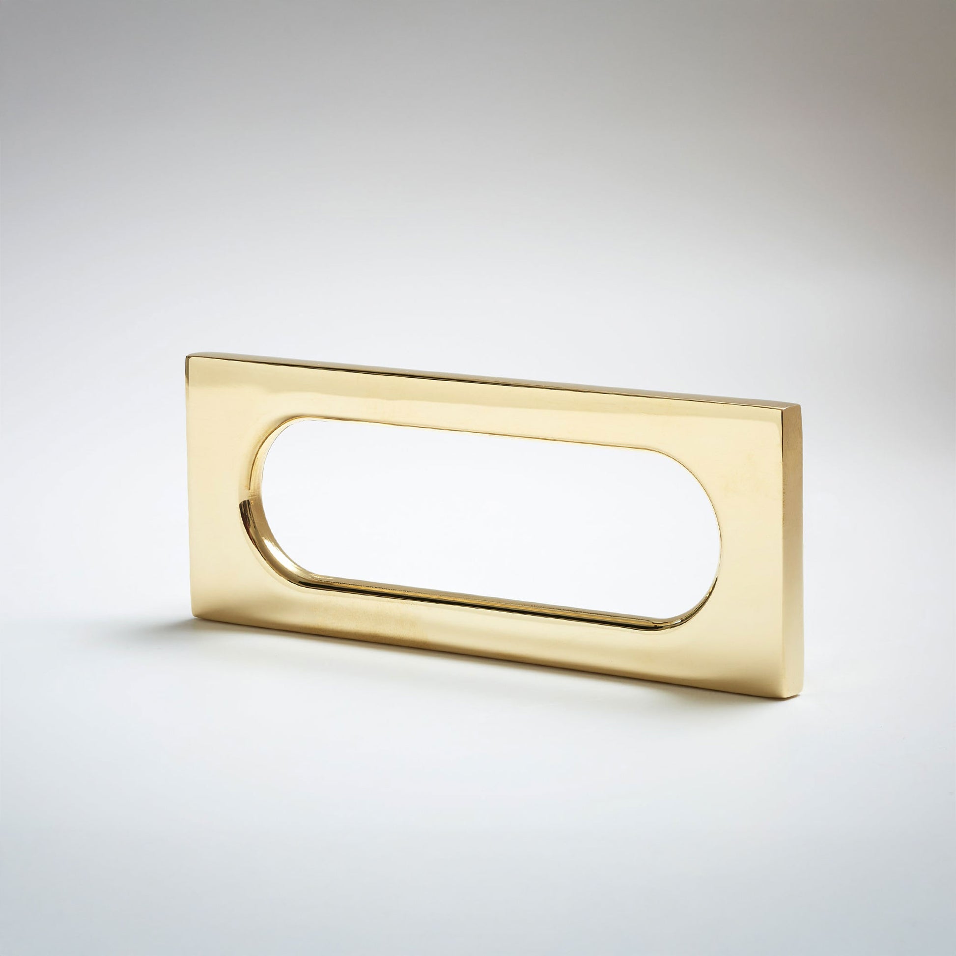 A polished brass rectangular pull handle with an oval cutout, shown on a light gray gradient background.