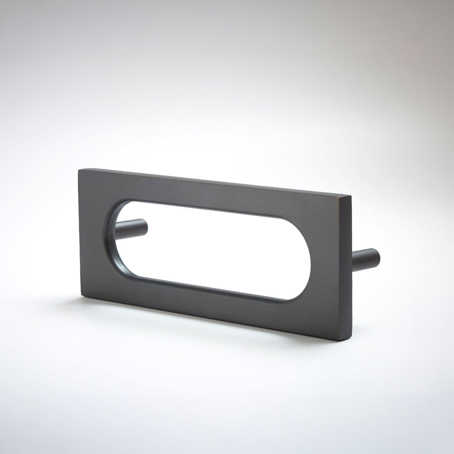 A matte black rectangular drawer pull with an elongated oval cutout, shown on a clean light gray 